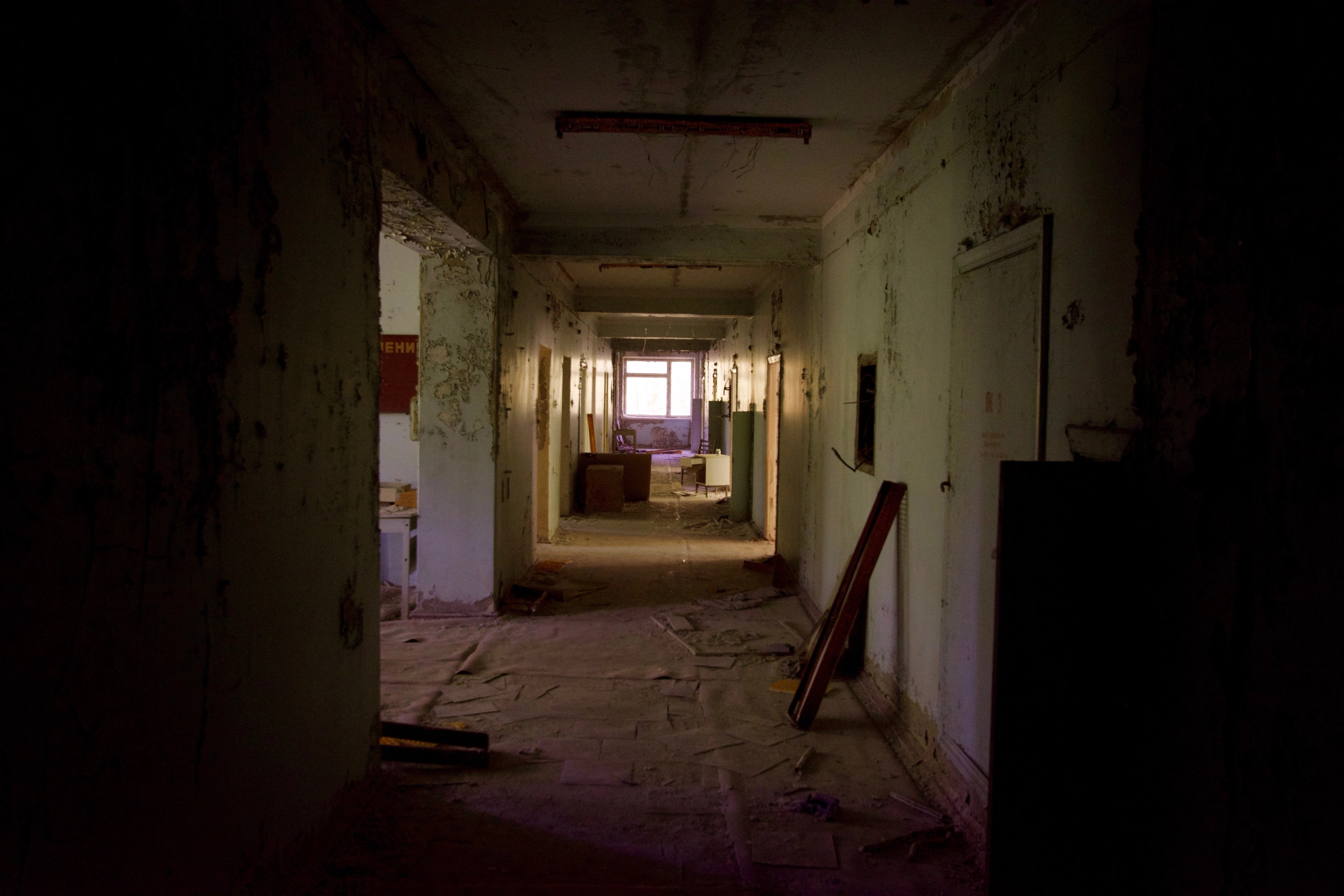 A dim corridor recedes through an abandoned building.