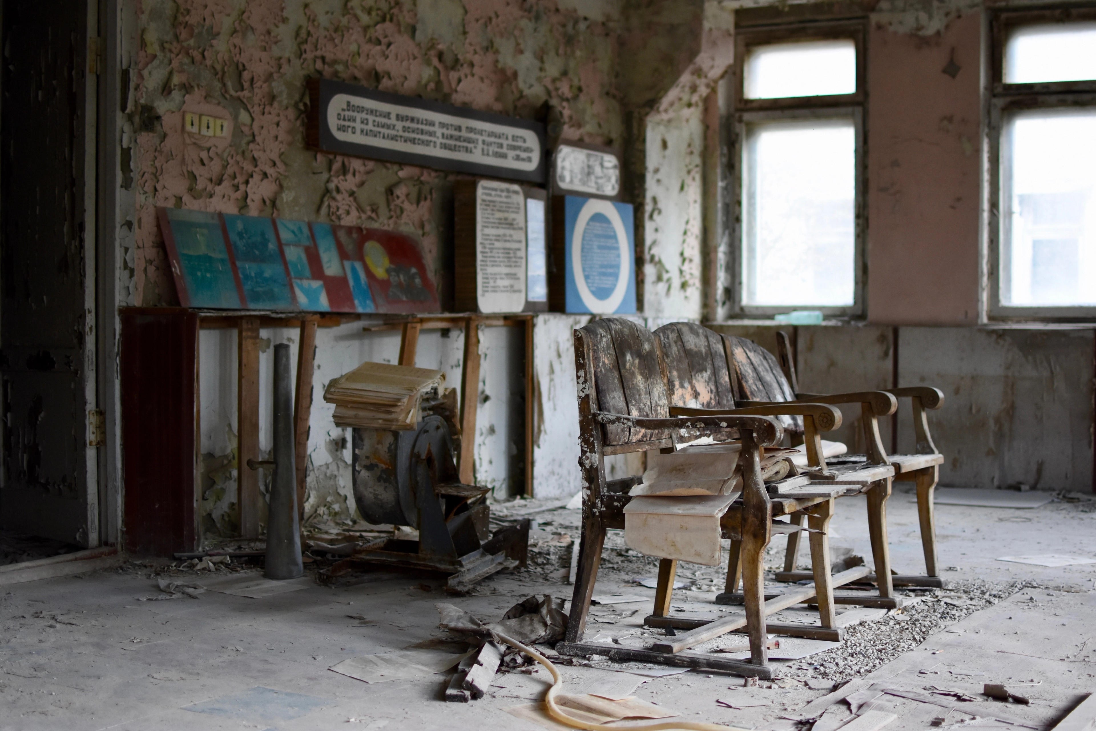 Old desks and an educational display in an abandoned classroom.