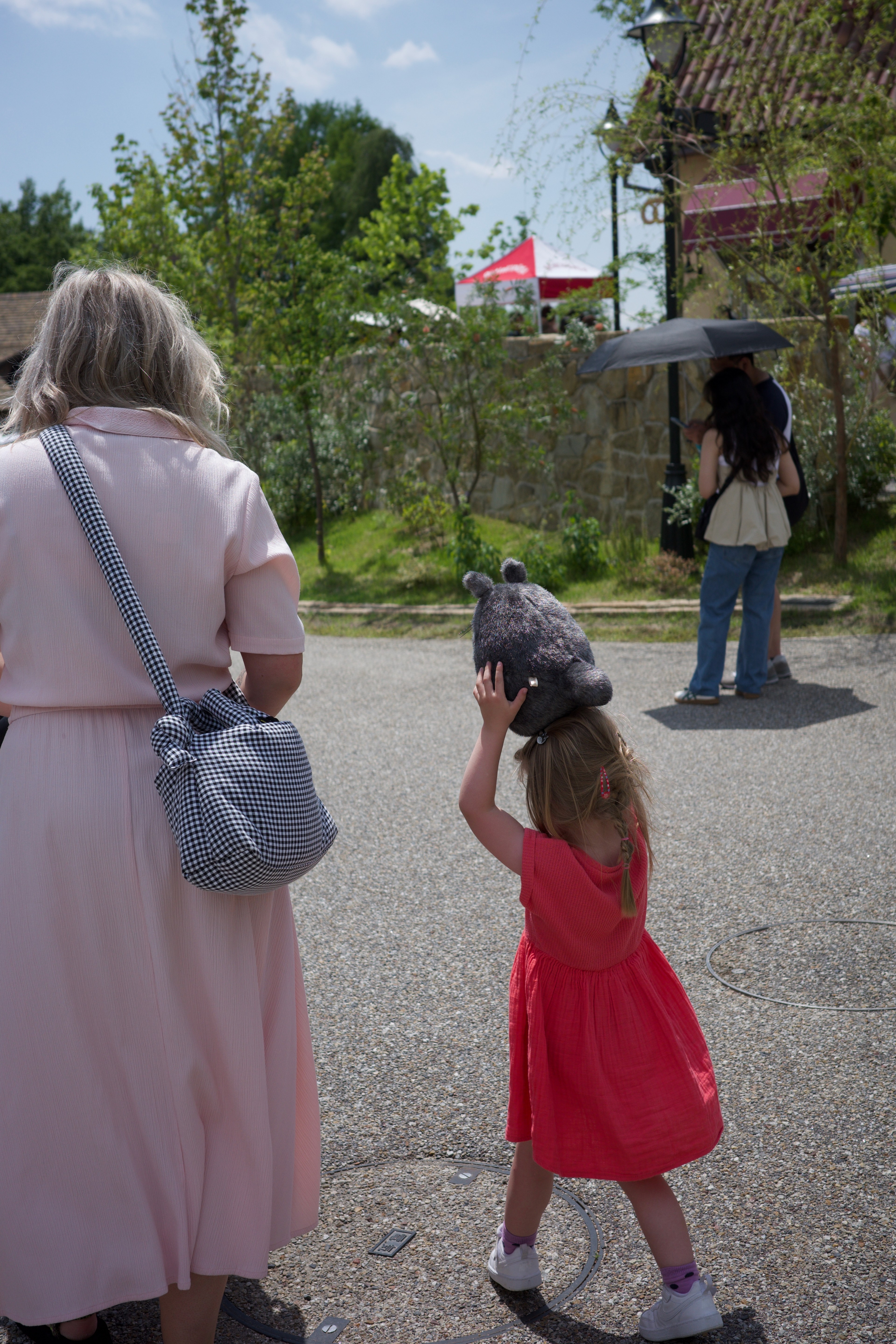 An adult and child walk toward an outdoor attraction.