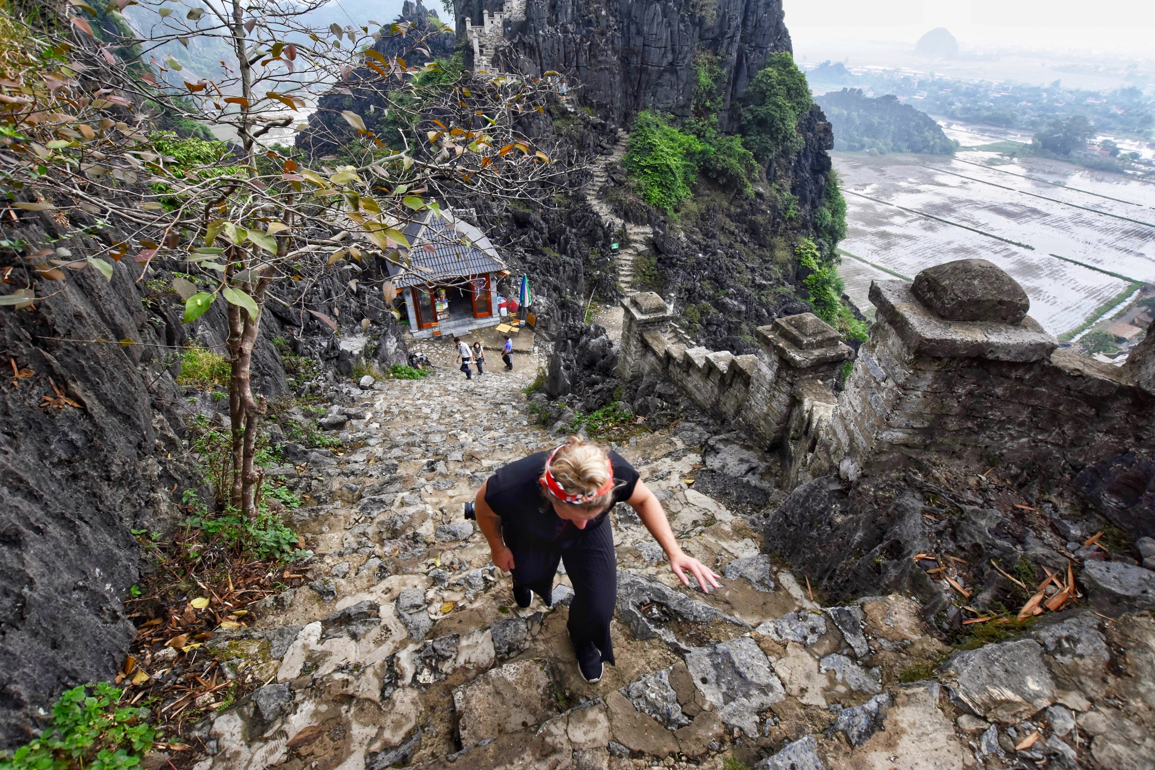 A person climbs steep stone steps cut into a rocky hillside.