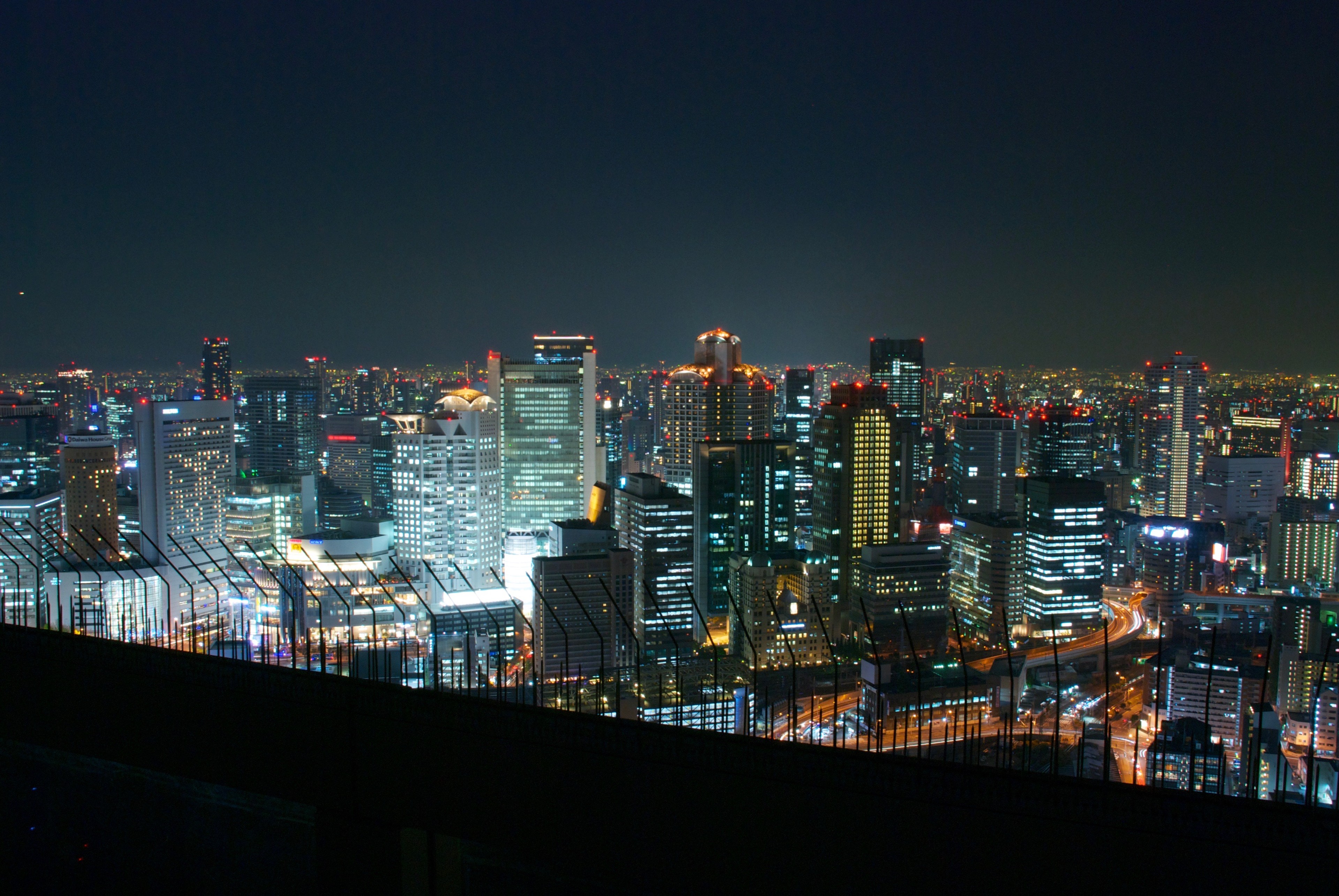 A high-angle night view of illuminated buildings across the city.