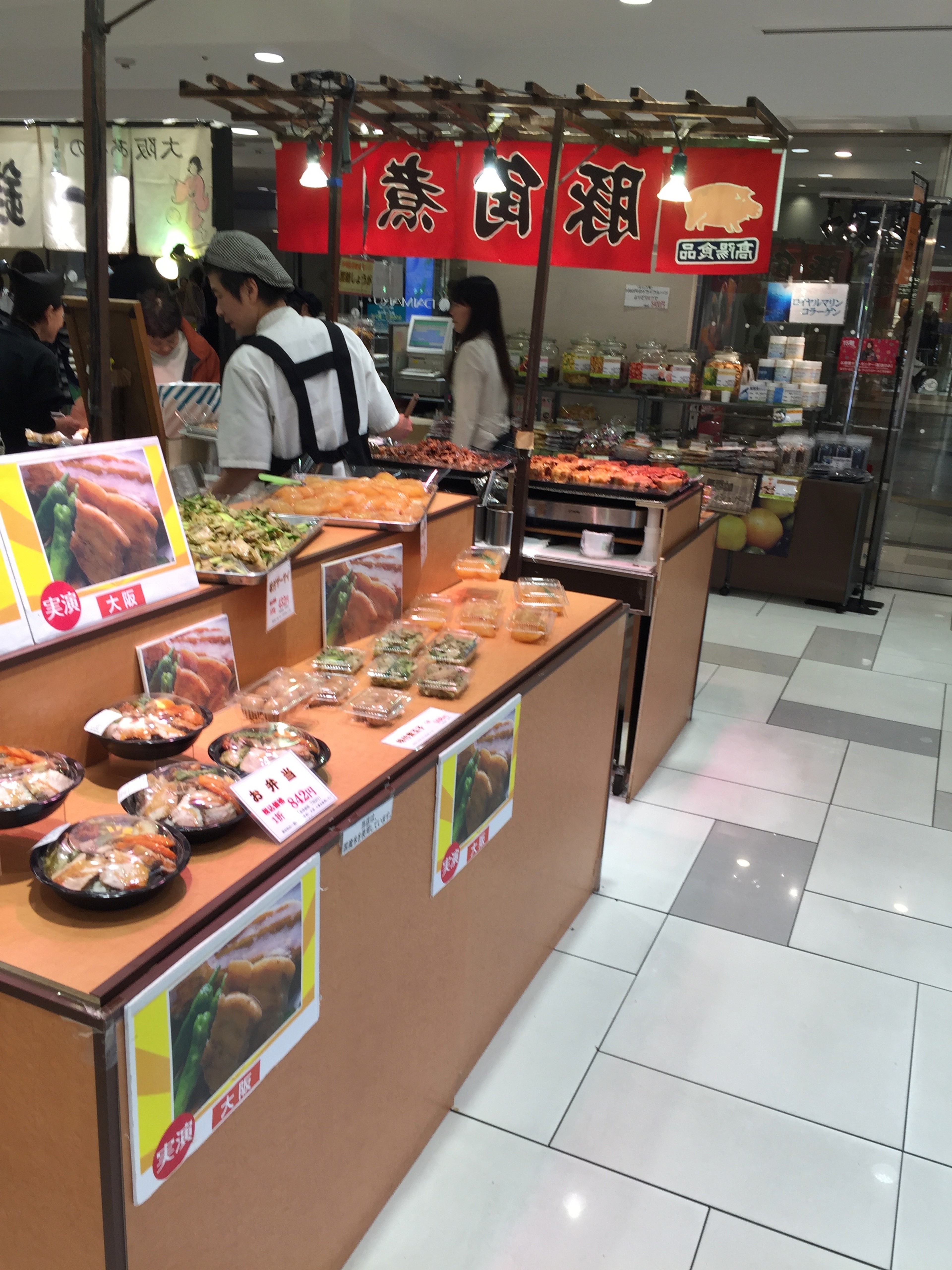 A small market kiosk displays packaged goods beneath red lanterns.