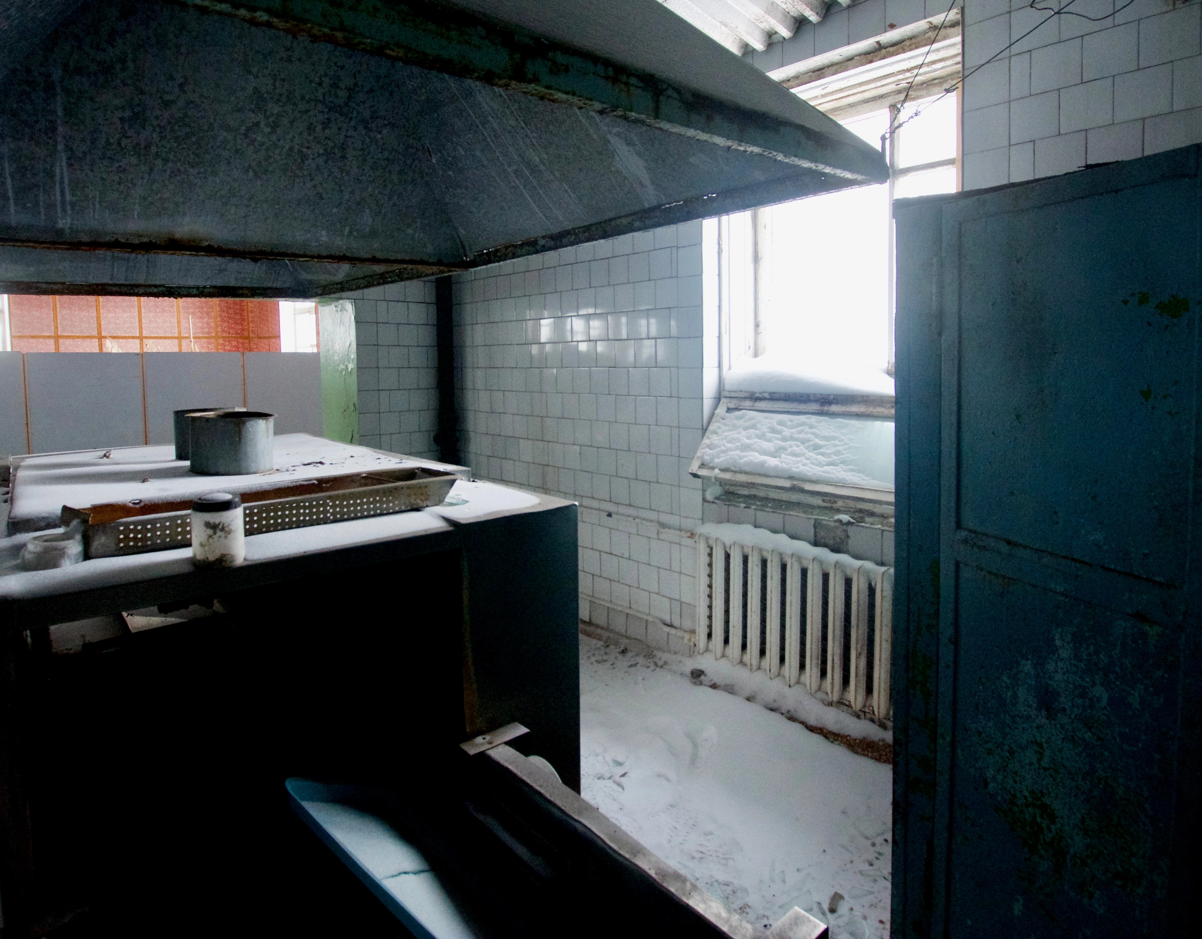 An old tiled kitchenette with a sink and window.