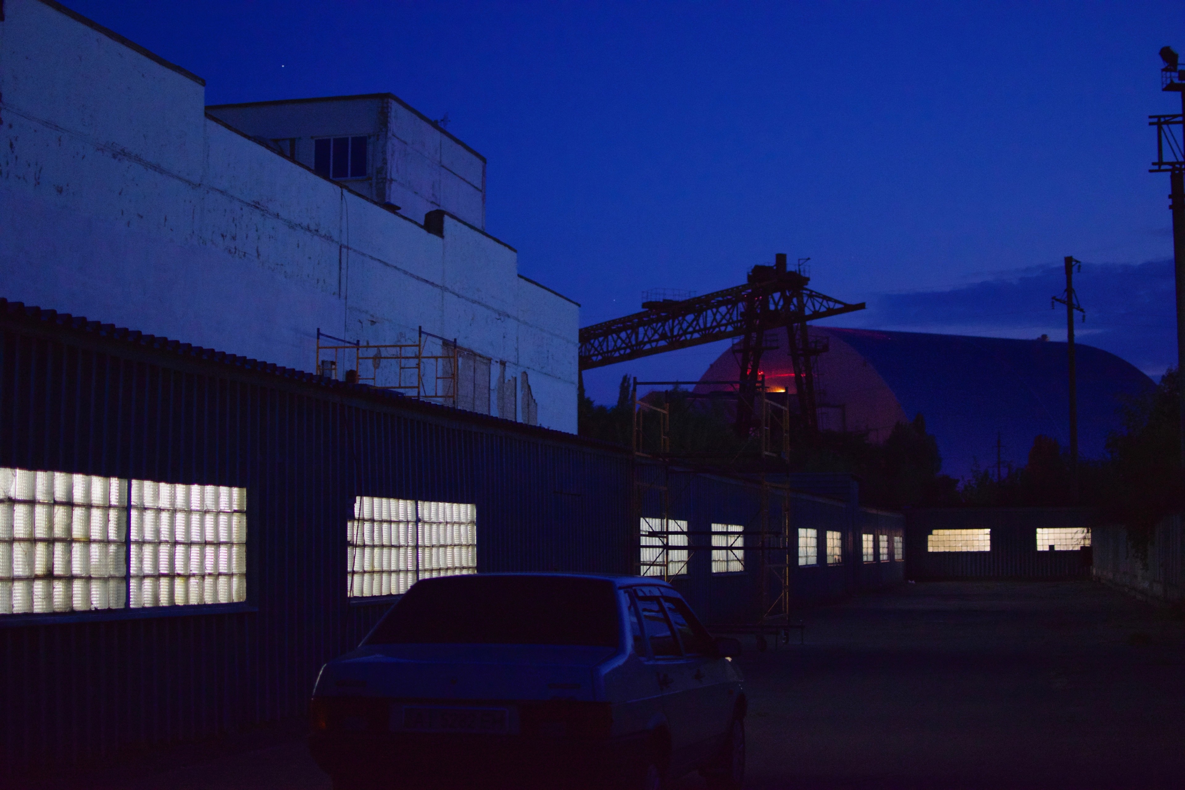 An industrial building glows blue against the night sky.