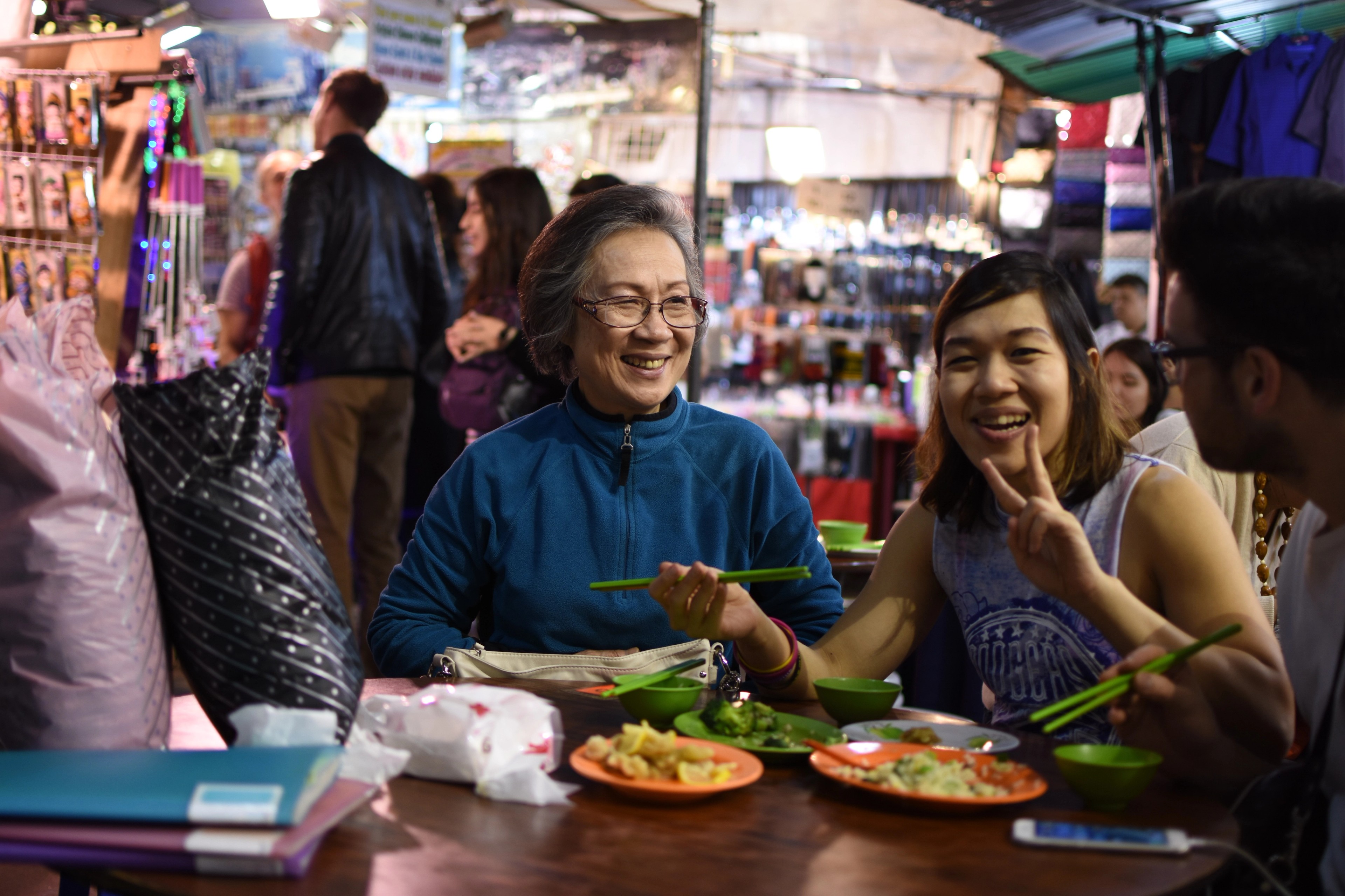 An older man and a younger woman share a meal at an outdoor table.