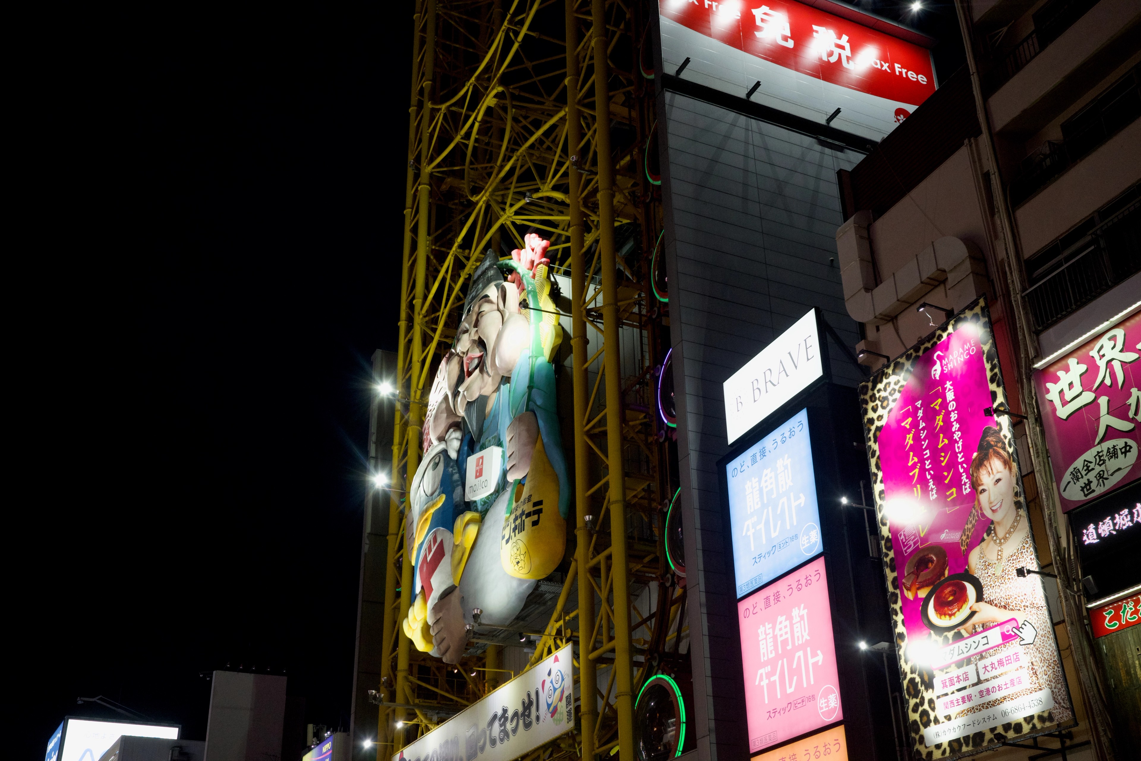A large illuminated character sign rises above storefronts.