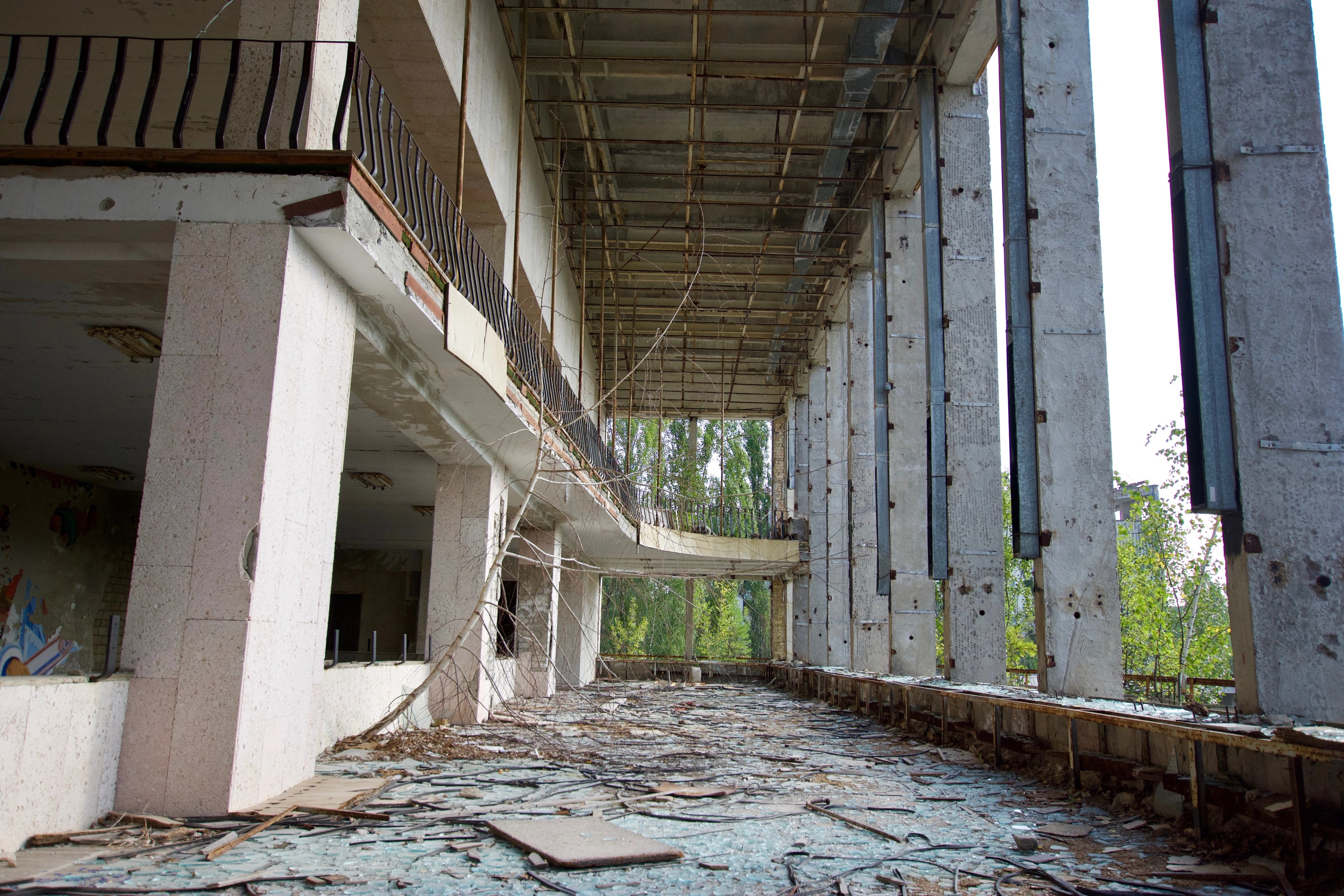 A long abandoned interior bordered by tall glass windows.