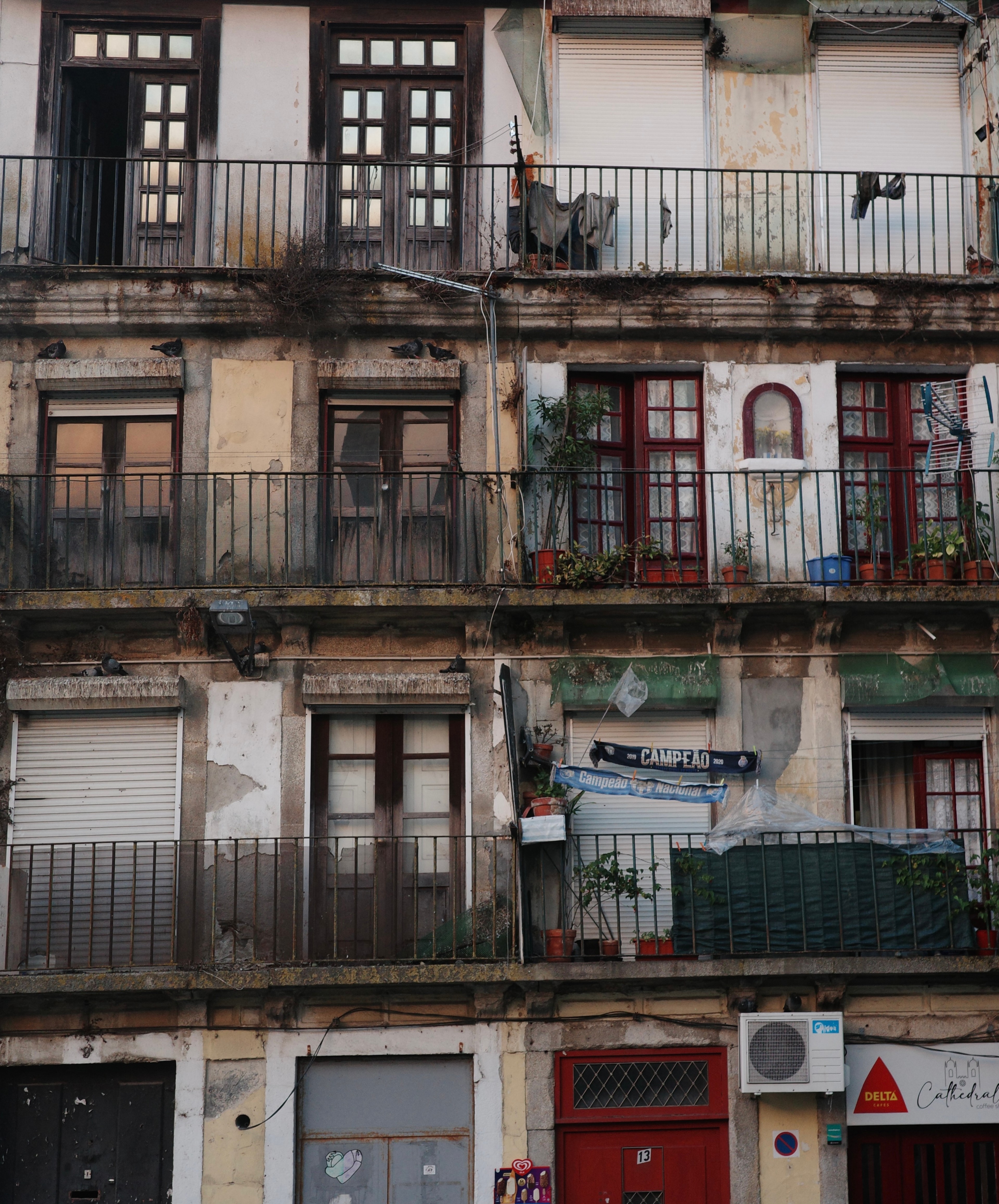 An aged apartment façade has tiled walls, balconies, and rows of windows.