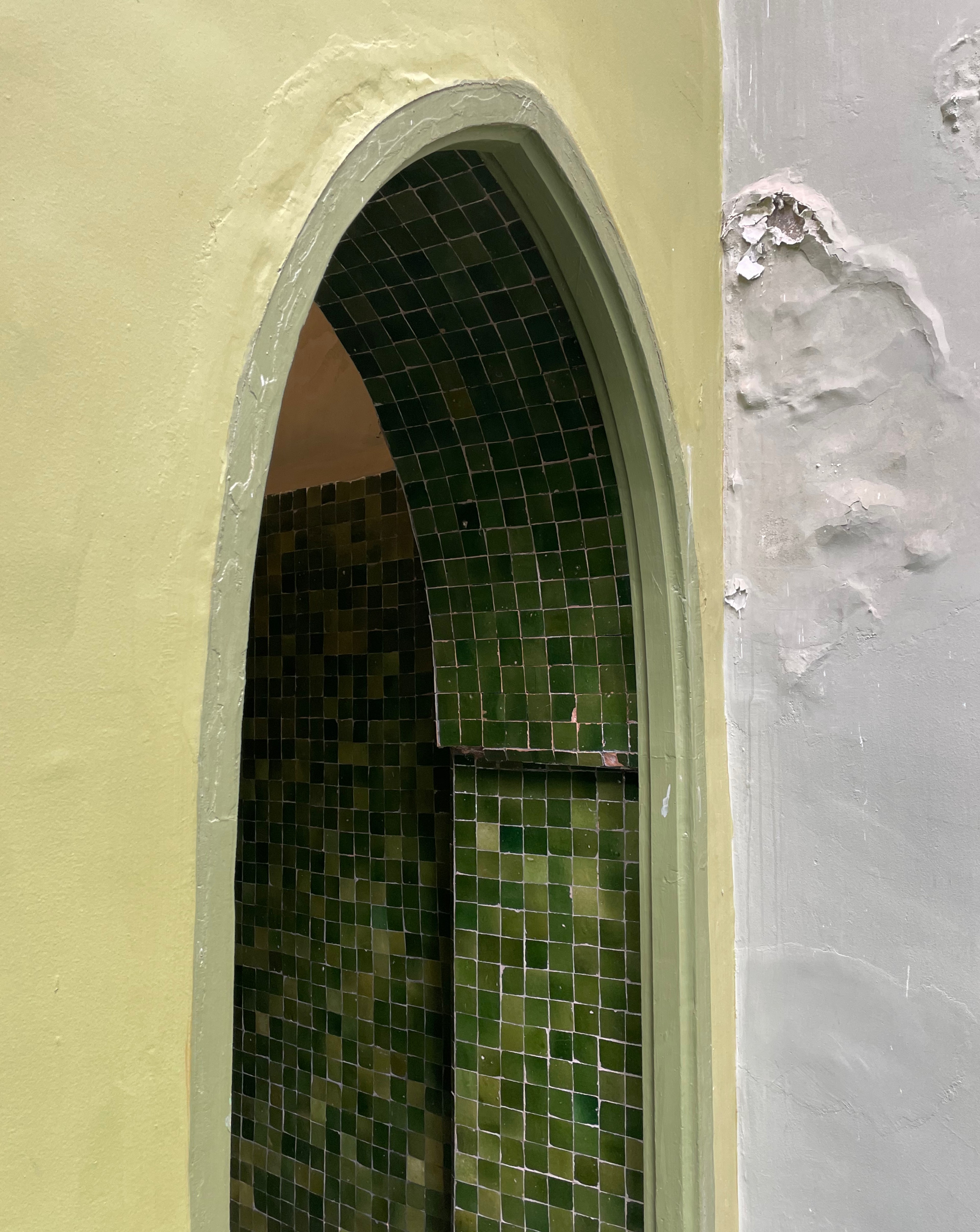 A narrow arched opening is lined with green patterned tiles.