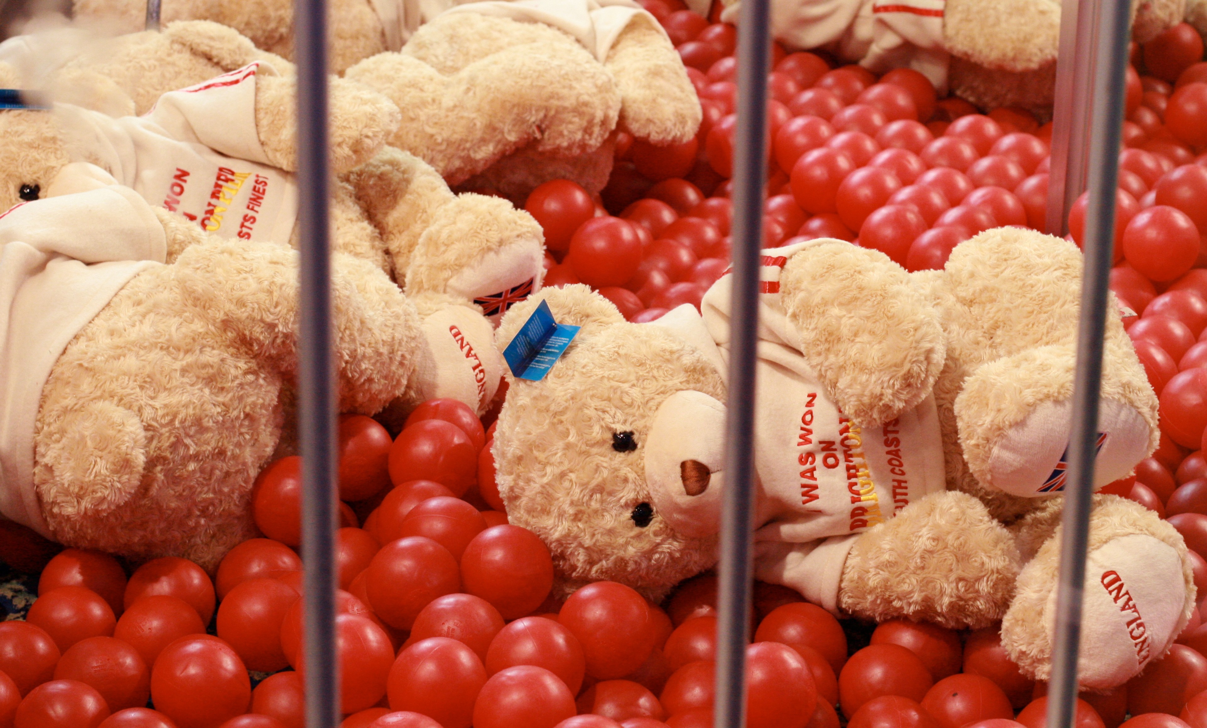 Plush toys are arranged behind red balls in a fairground game stall.