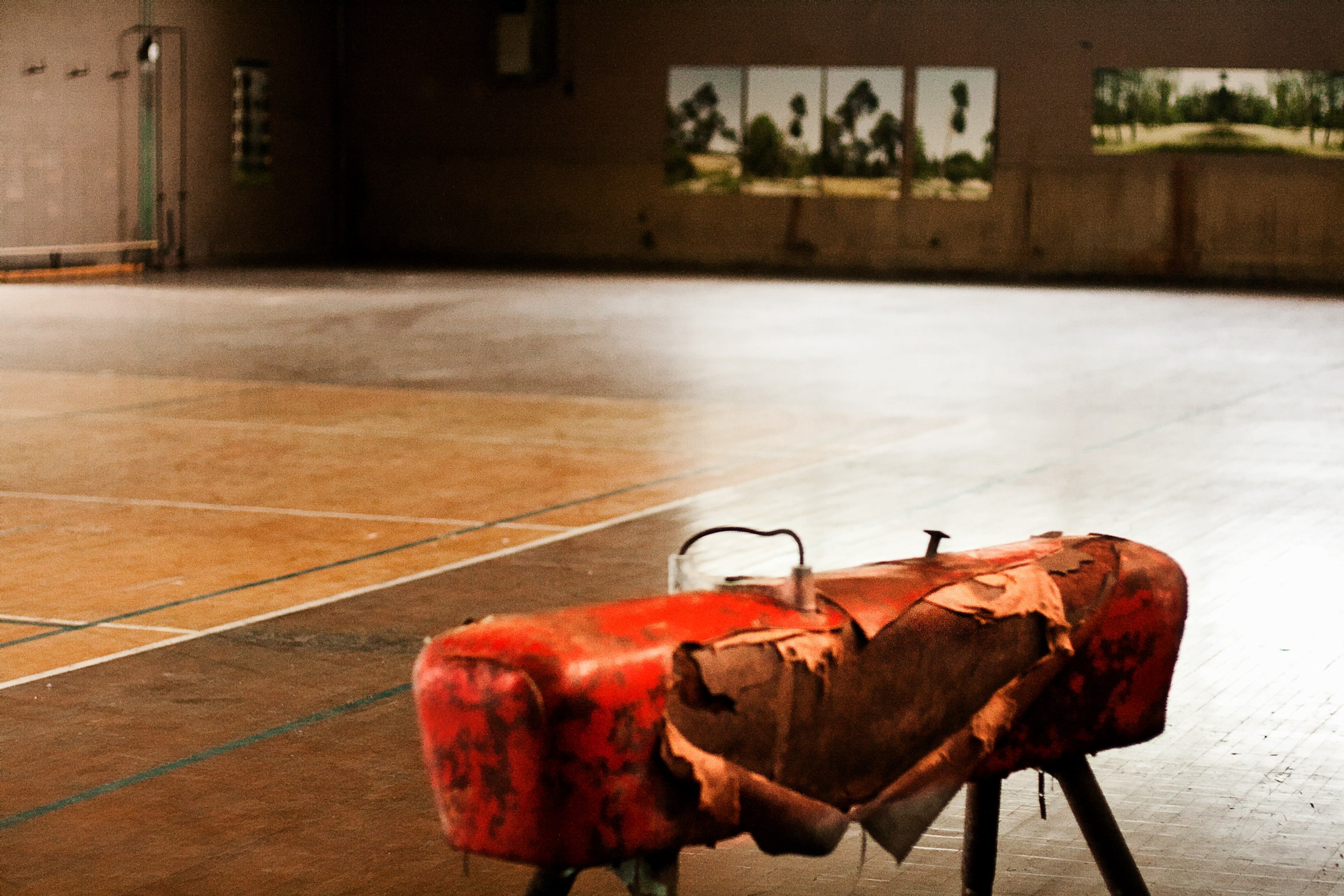 A red object lies on a polished floor in a large empty hall.
