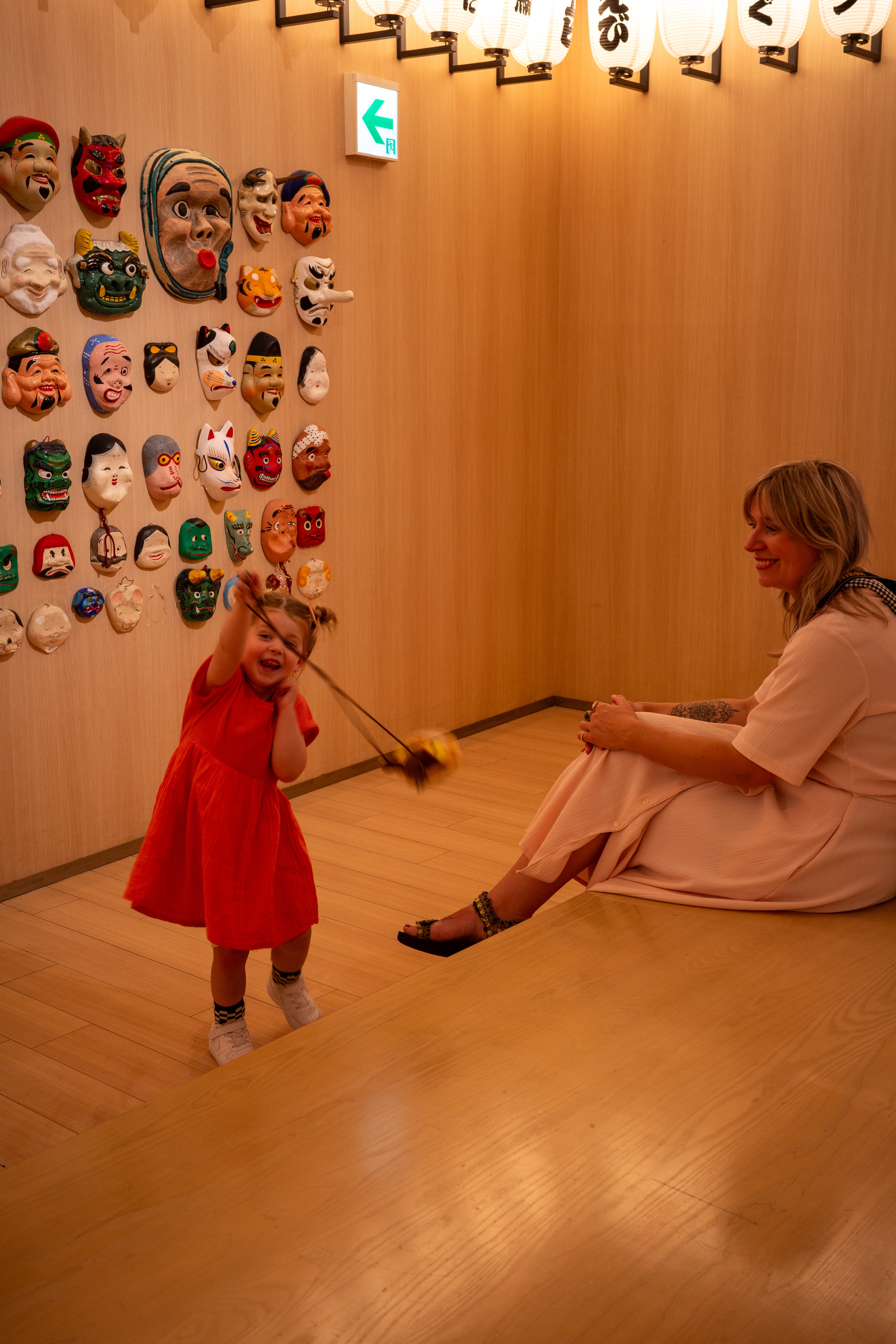 A child in a red dress stands near an adult inside an exhibit.
