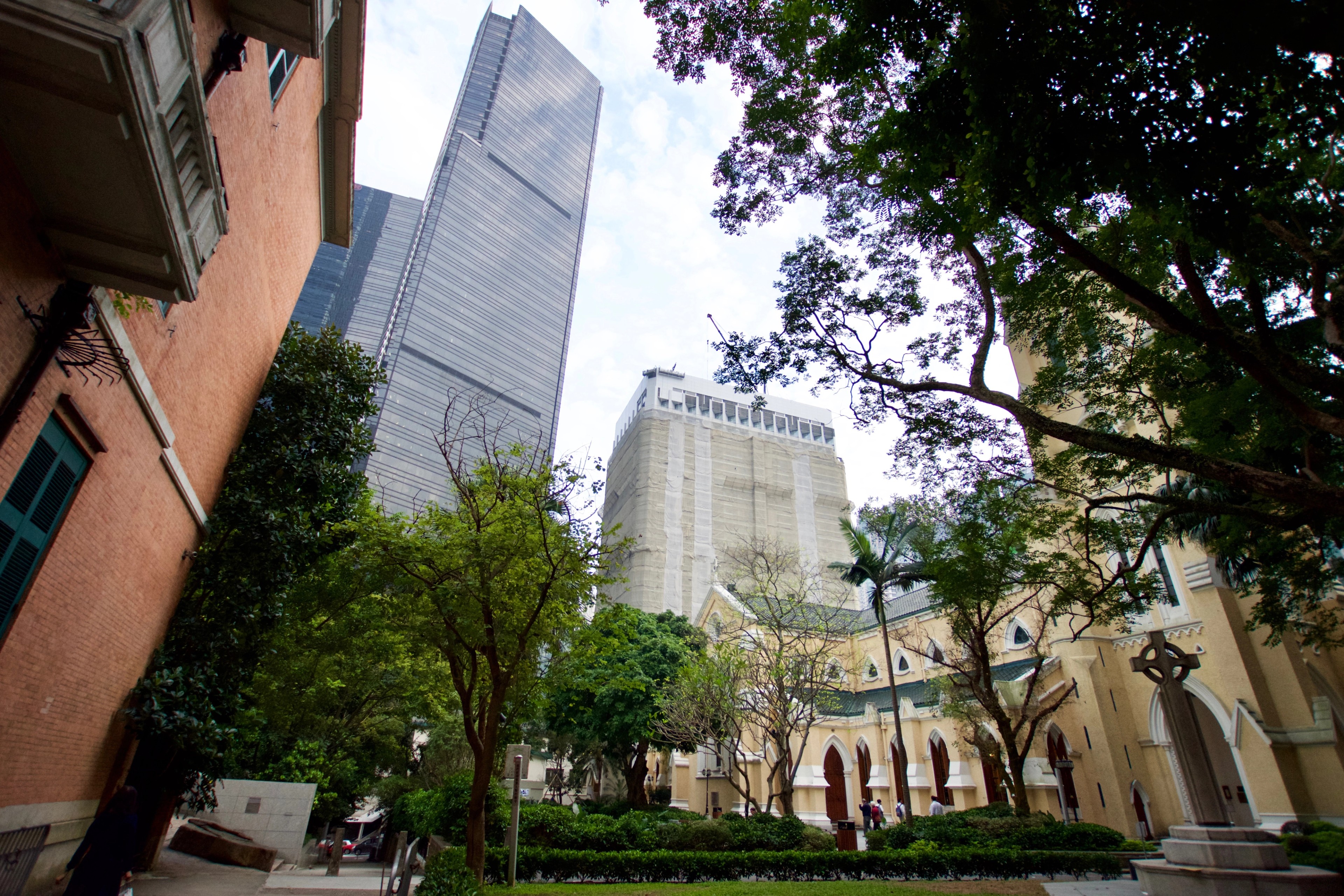 Historic low-rise buildings and trees sit beneath a modern glass tower.
