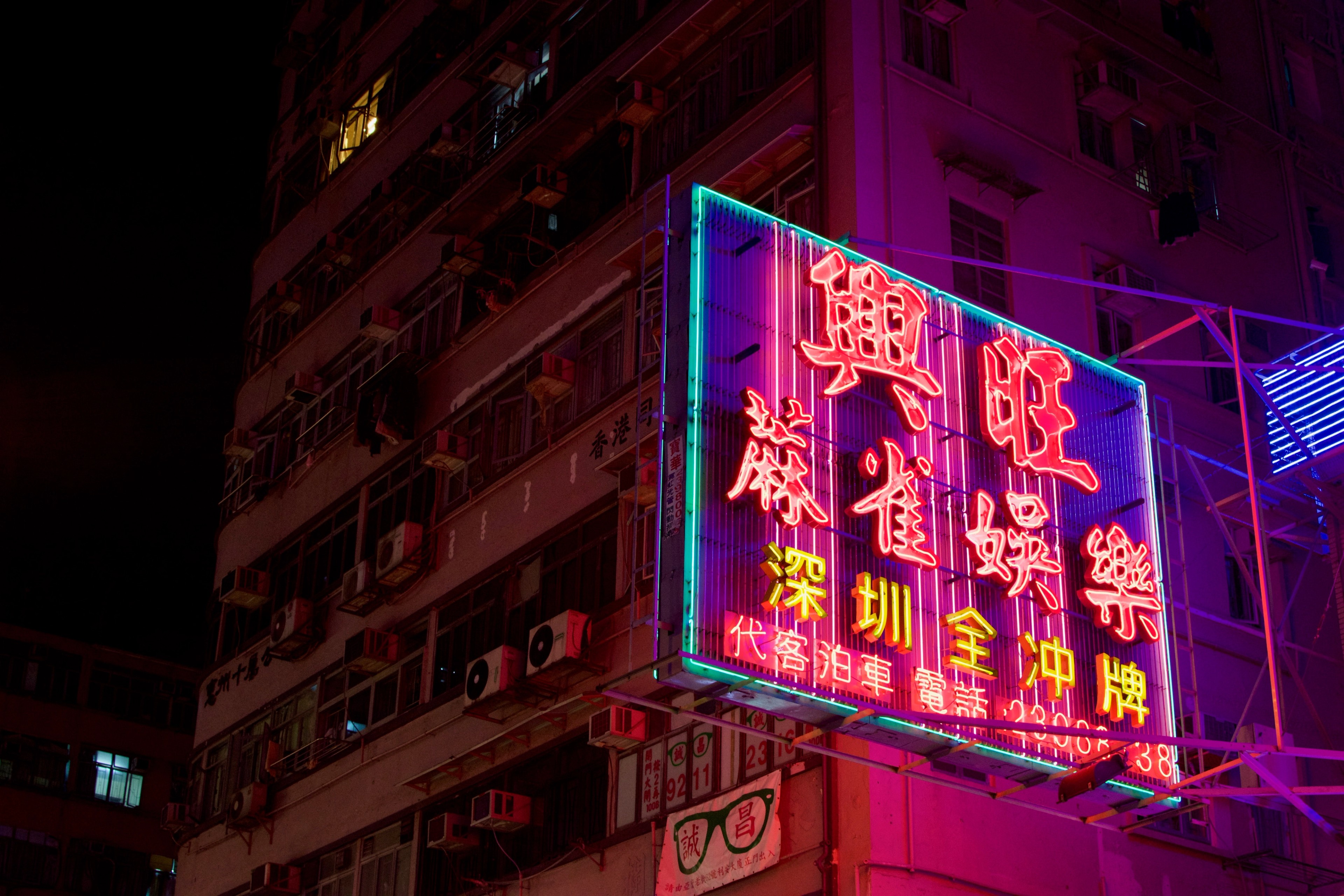 A red and blue neon seafood restaurant sign is mounted above the street.