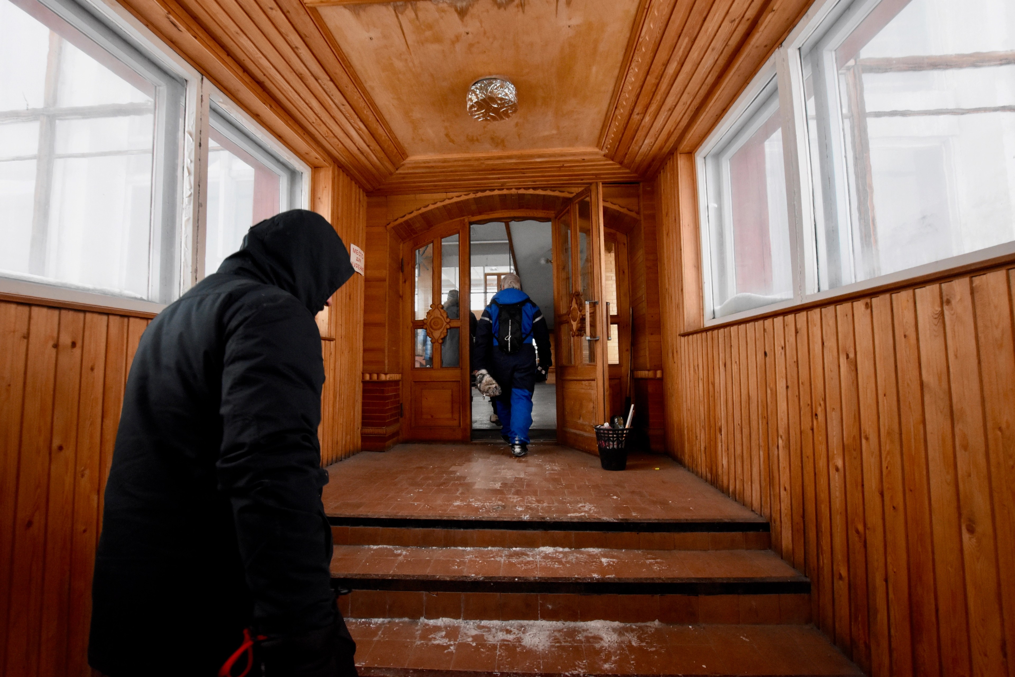 People walk through a wood-paneled interior hallway.