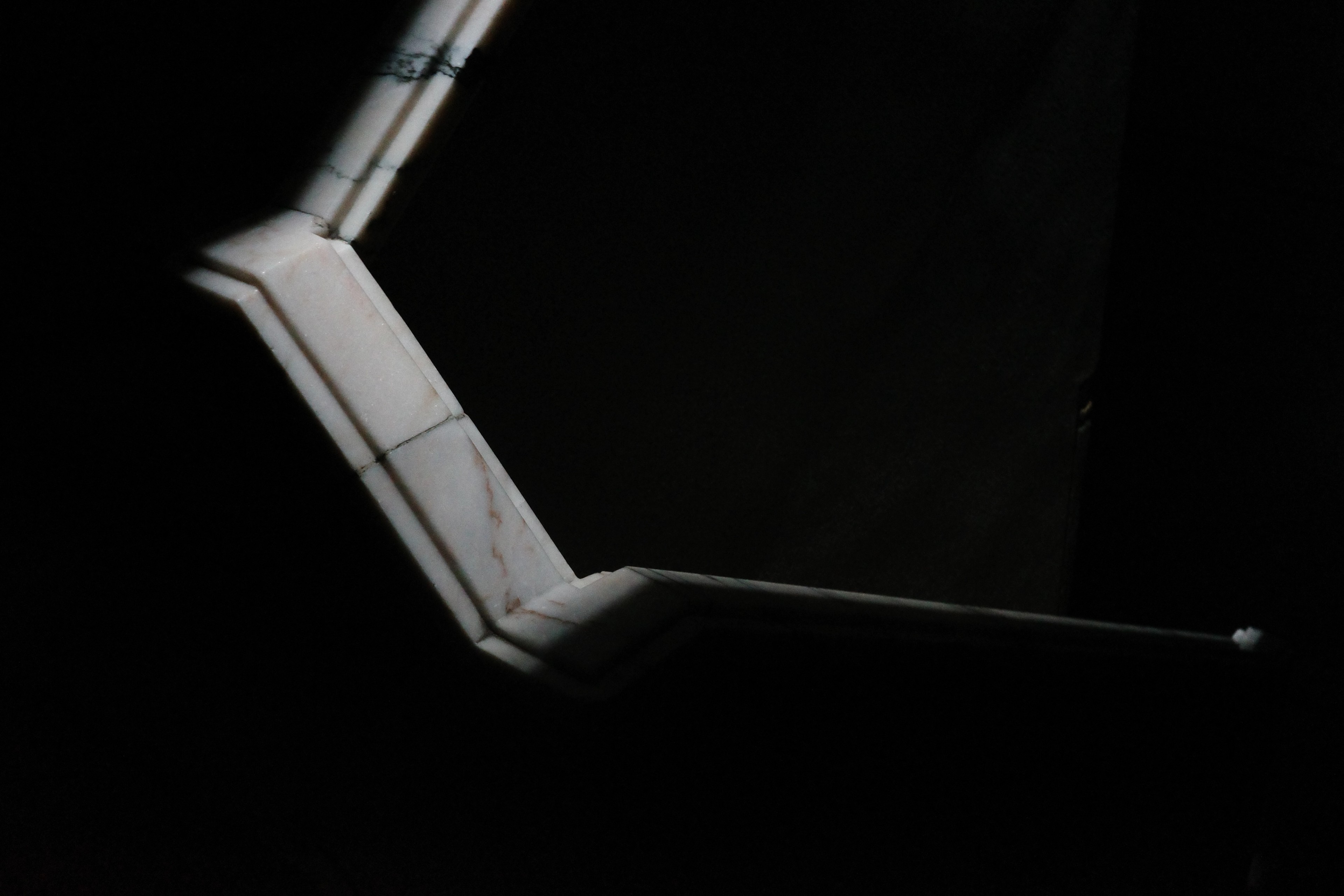 A narrow illuminated angular line cuts across a dark exhibition space.