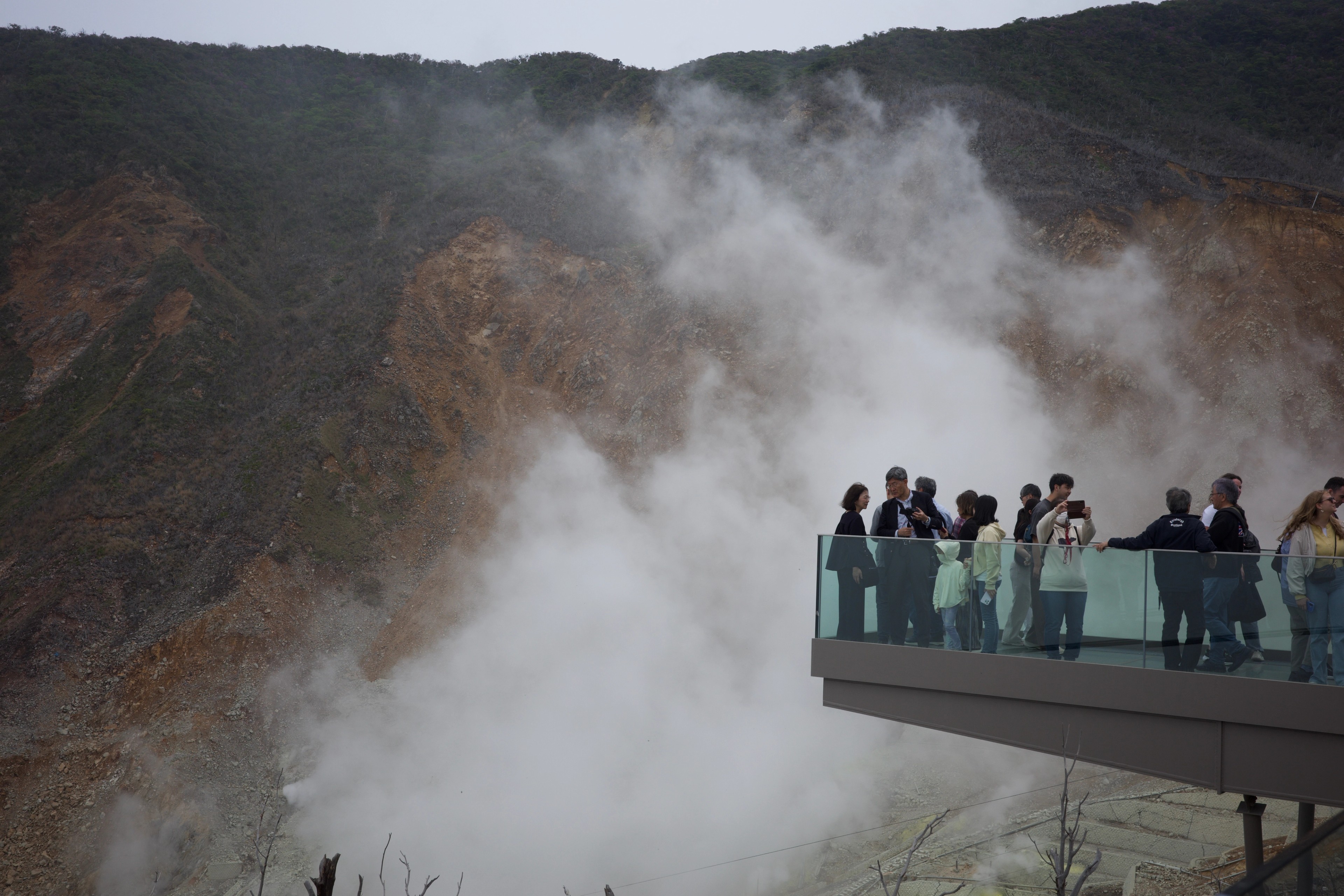 Visitors watch steam rise from a crater overlook.