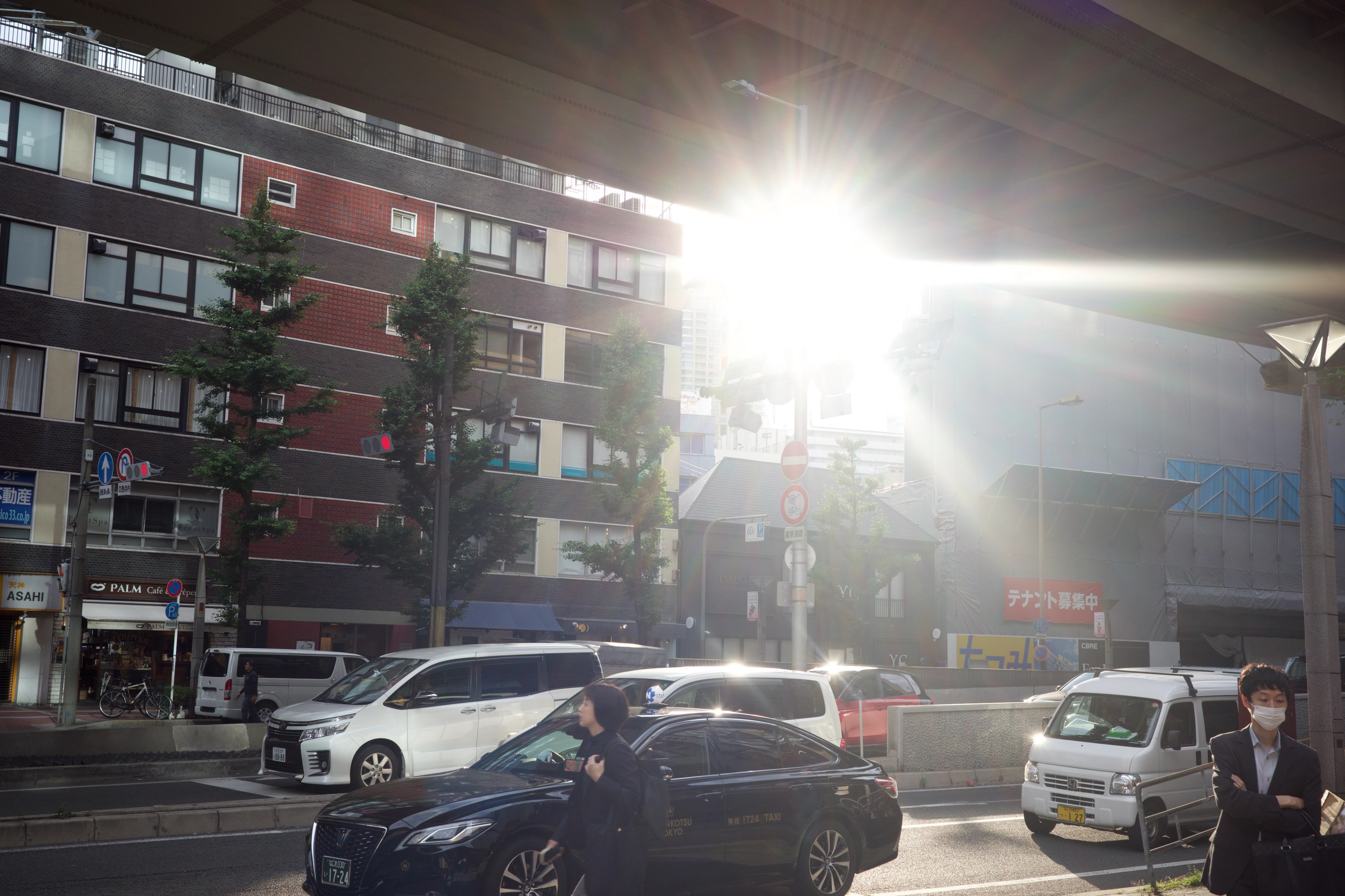 Traffic moves through a sunlit city intersection.