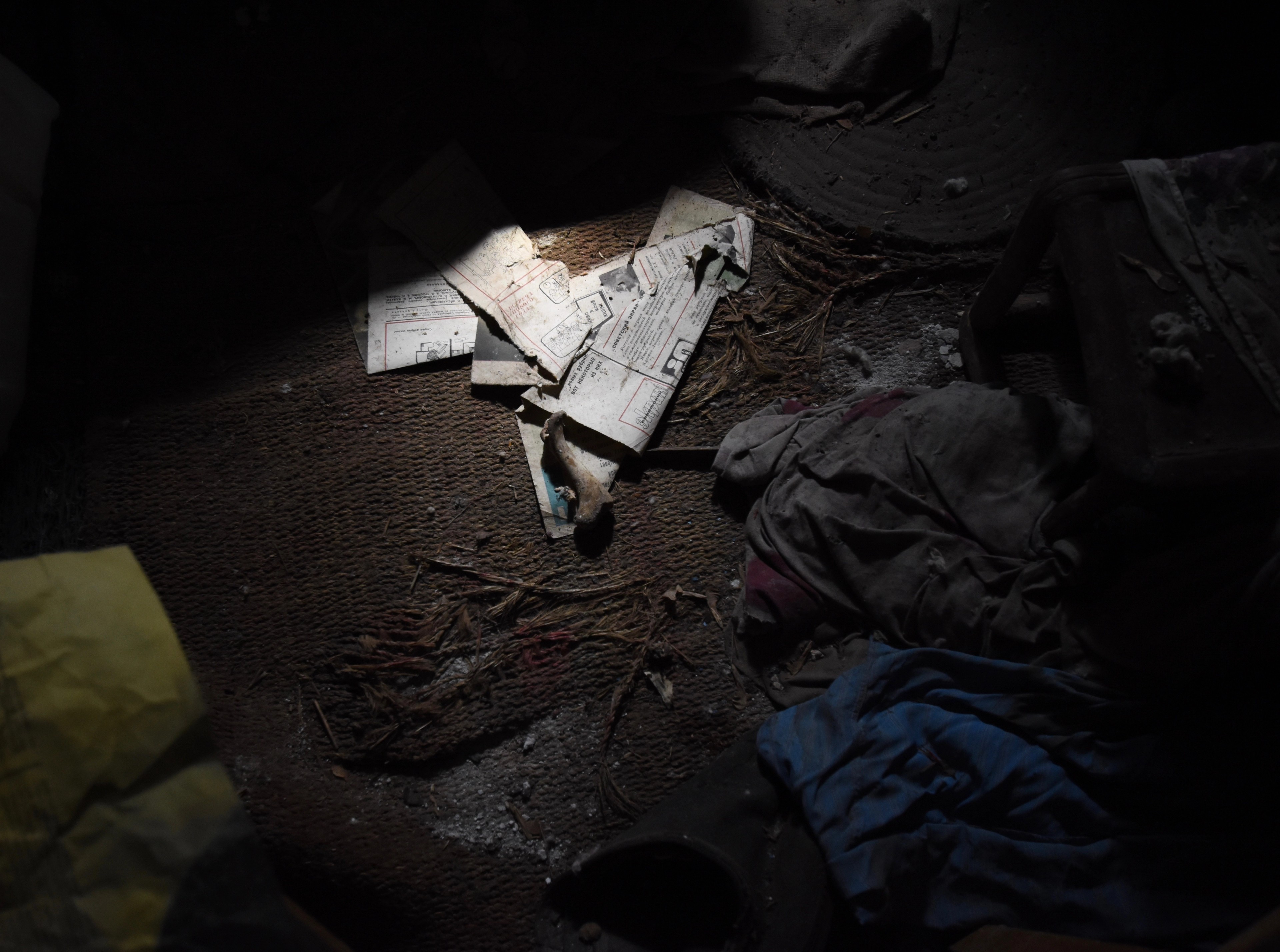 Broken objects lie across the floor of a dark room.