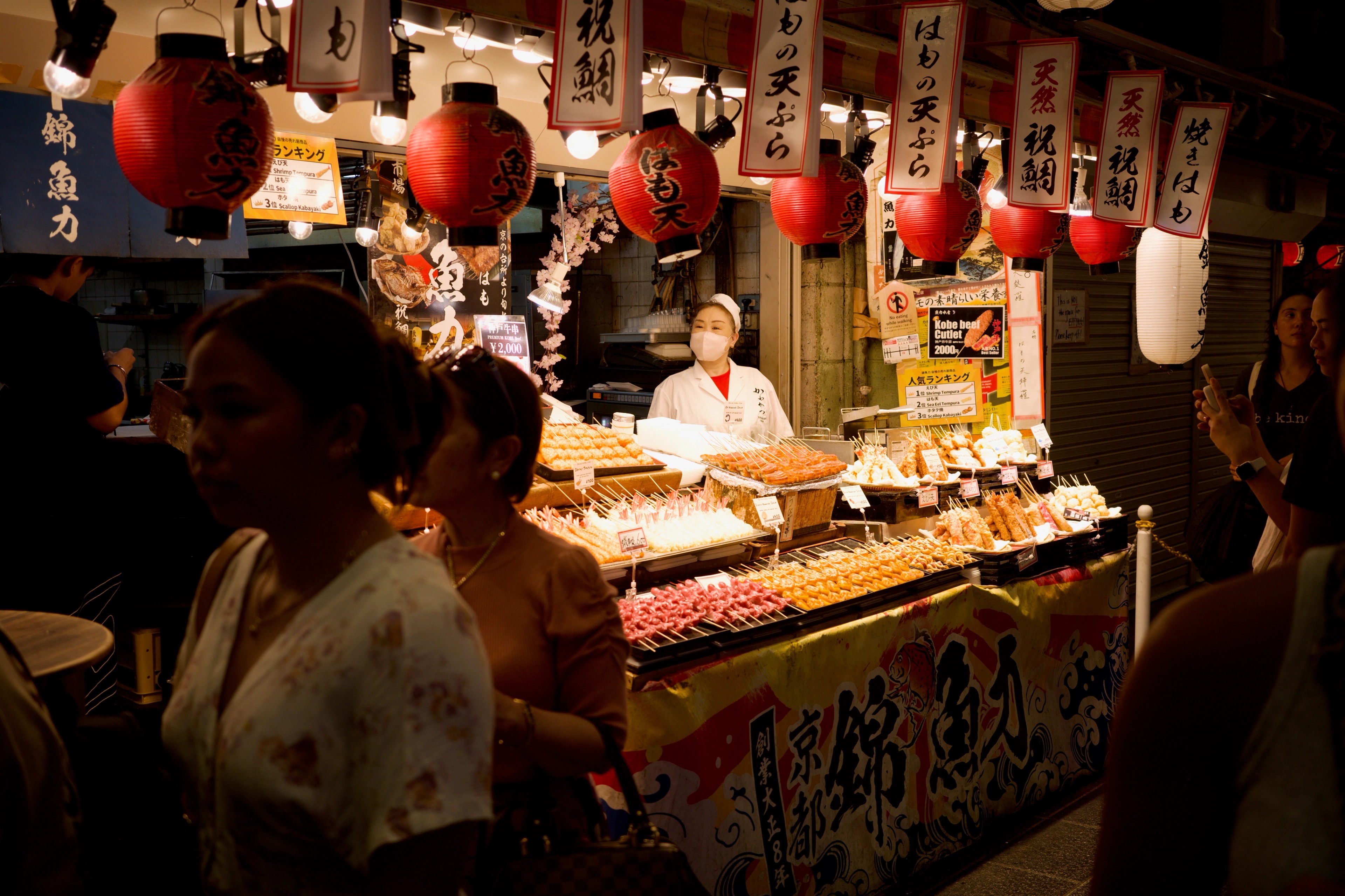 Customers browse a lantern-lit food stall.