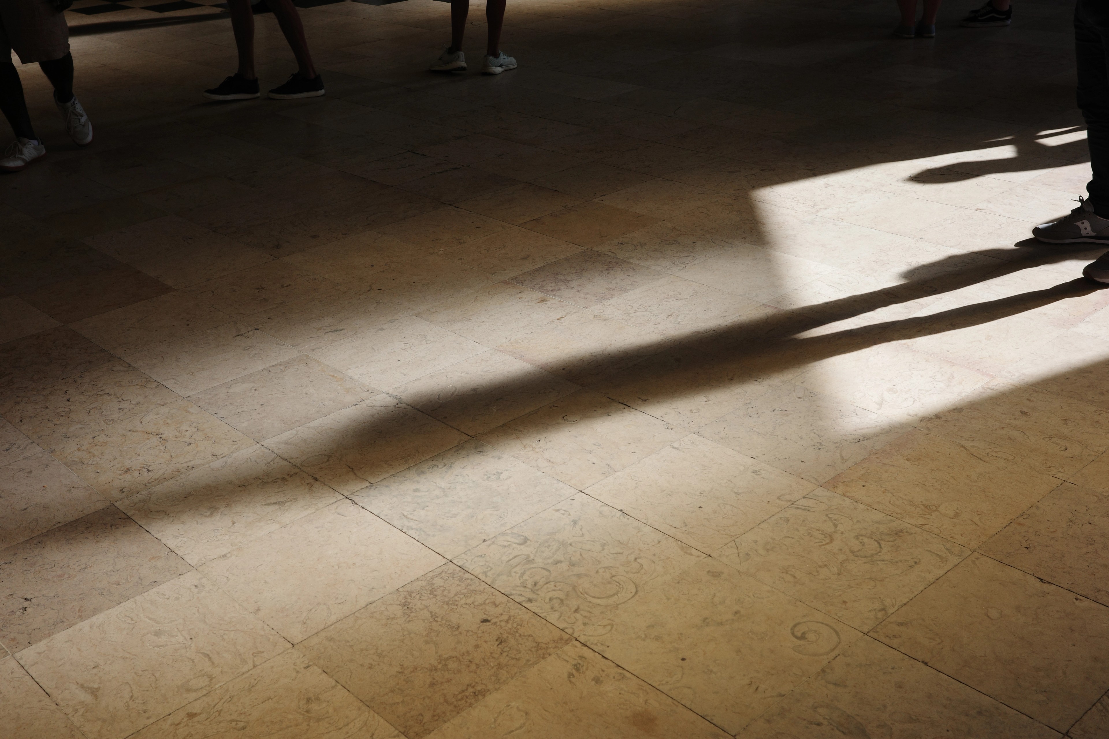 Late sunlight stretches across a bare stone floor inside a building.