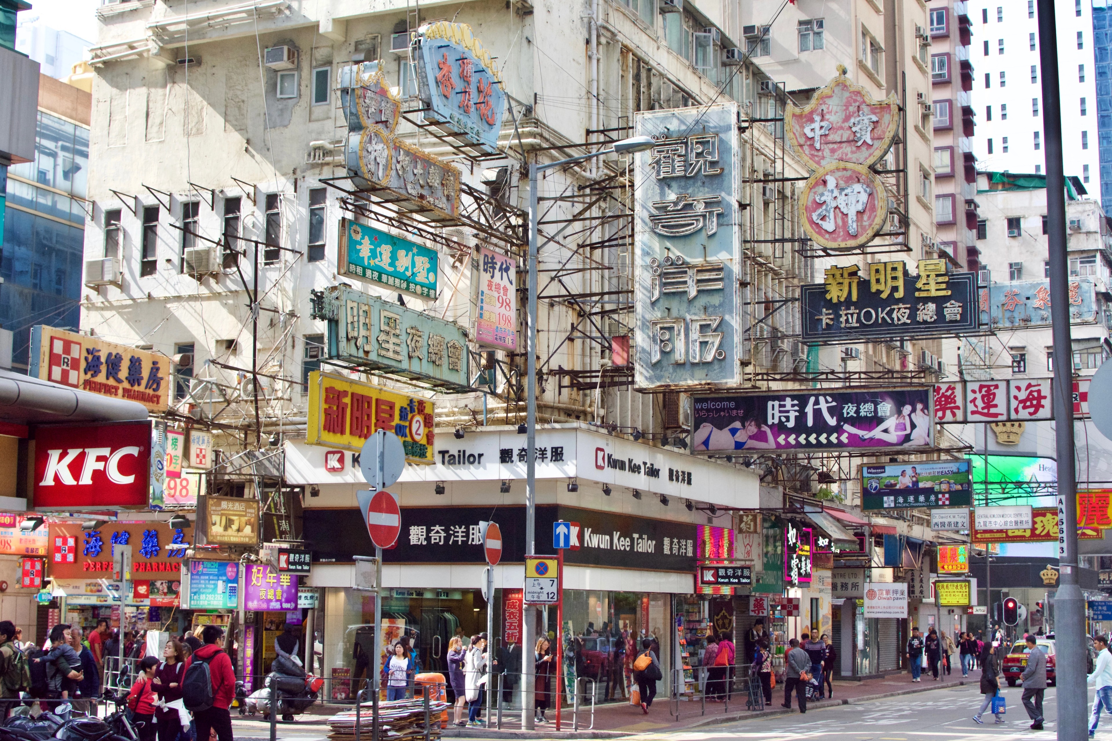 Shop signs crowd the façade above a busy Hong Kong street.
