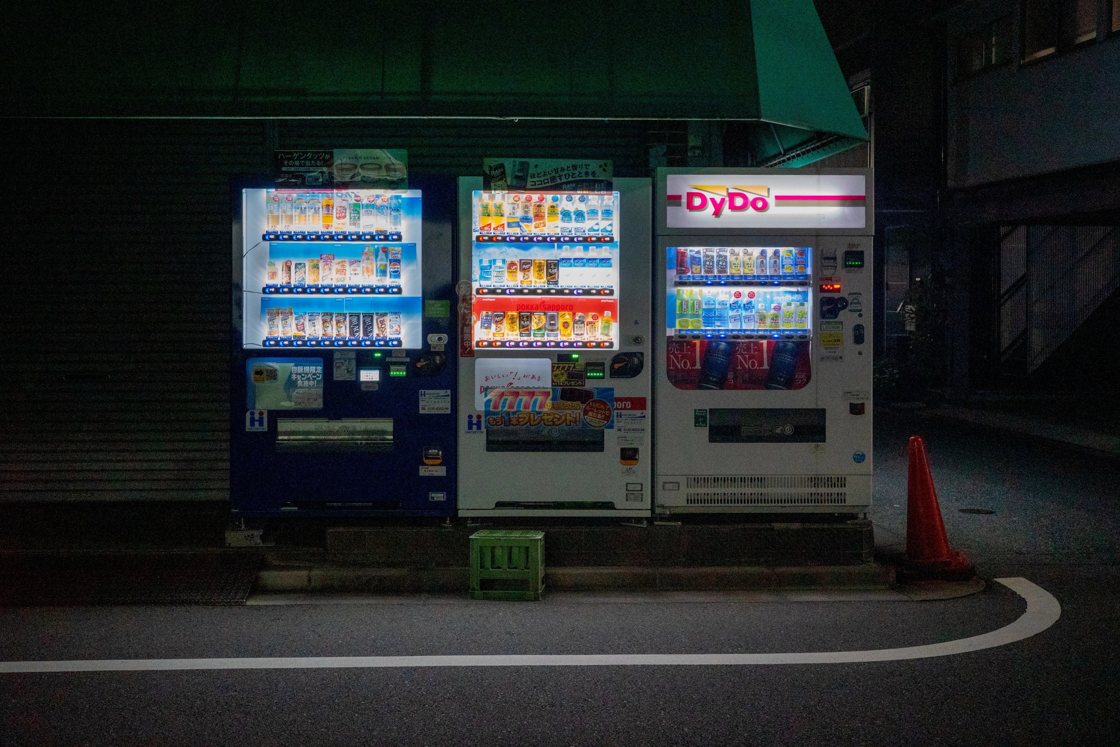 Vending machines glow on a dark street.