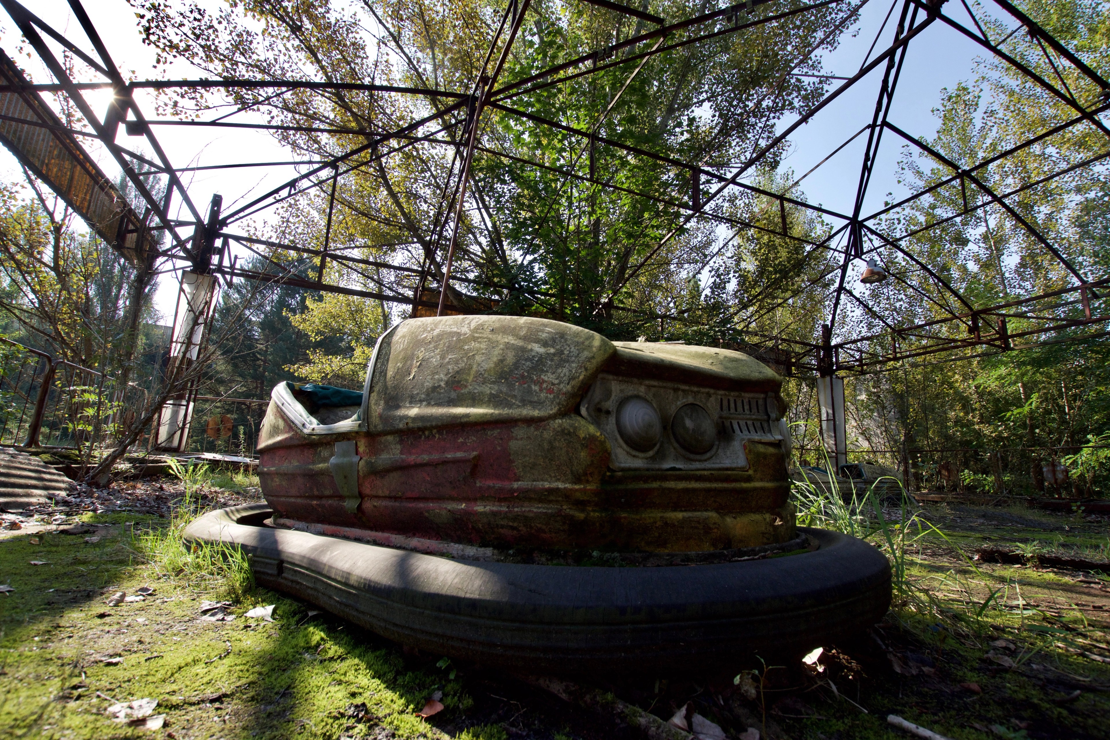 A weathered bumper car beneath a metal framework.