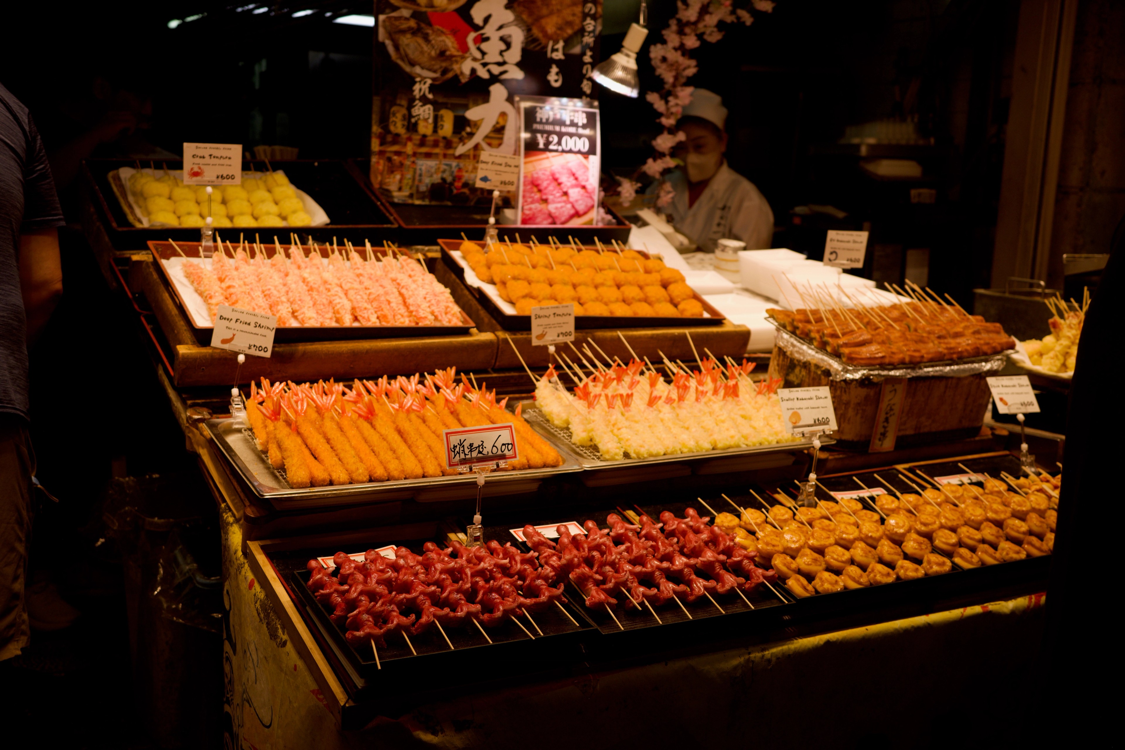 Trays of skewered and fried foods line a market stall.