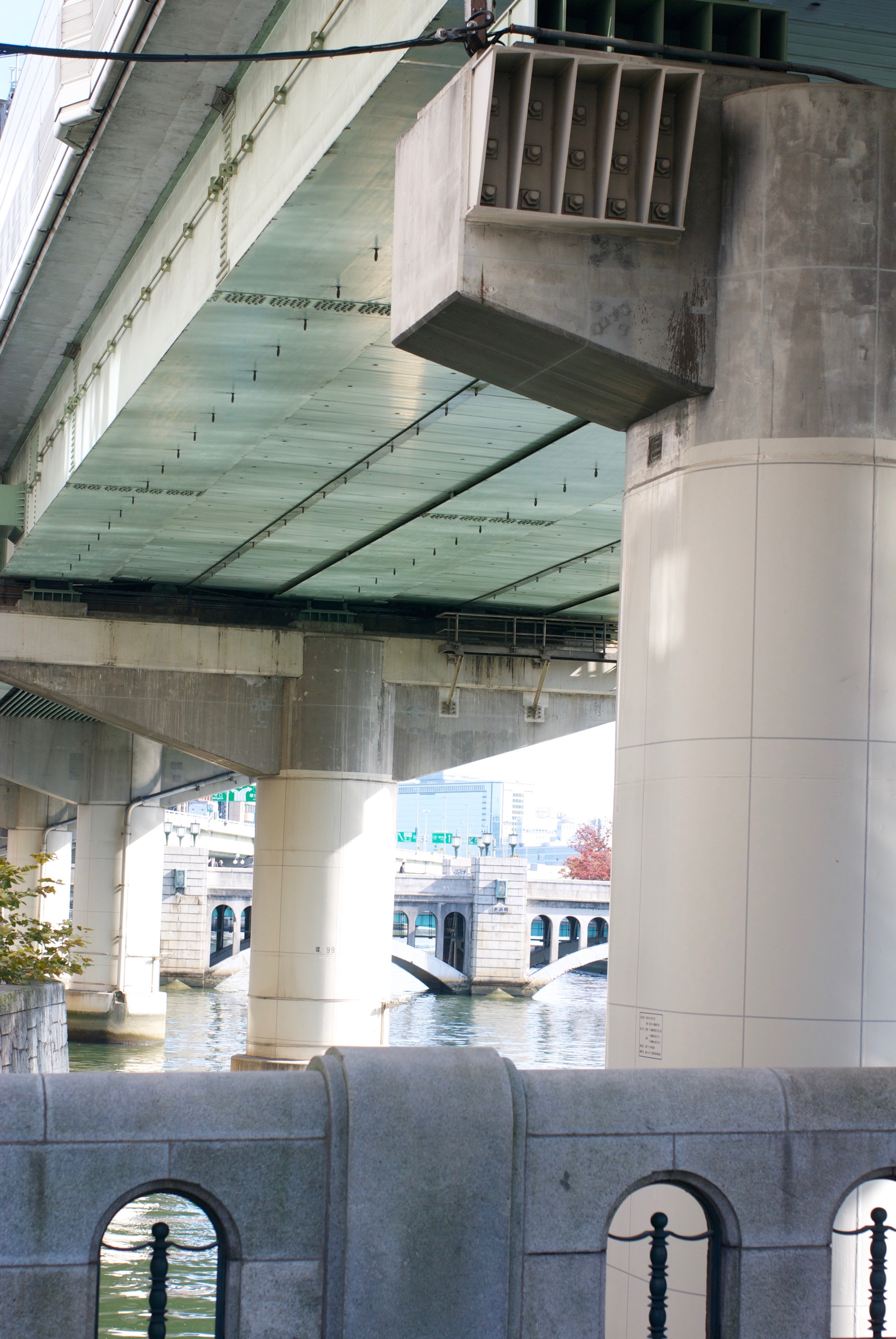 The underside of an elevated concrete roadway rises above the street.