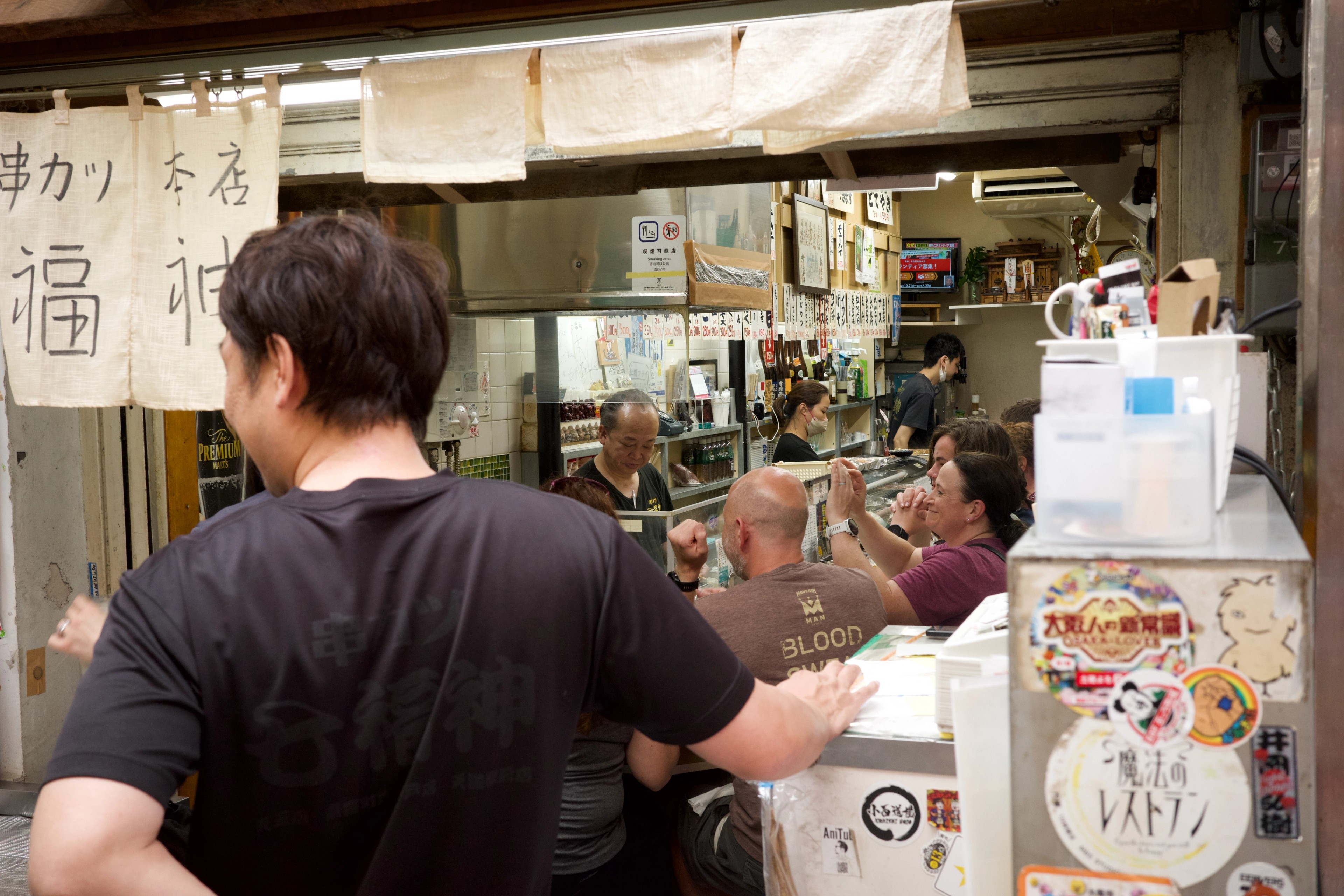 A customer speaks to a worker at a small food stall.