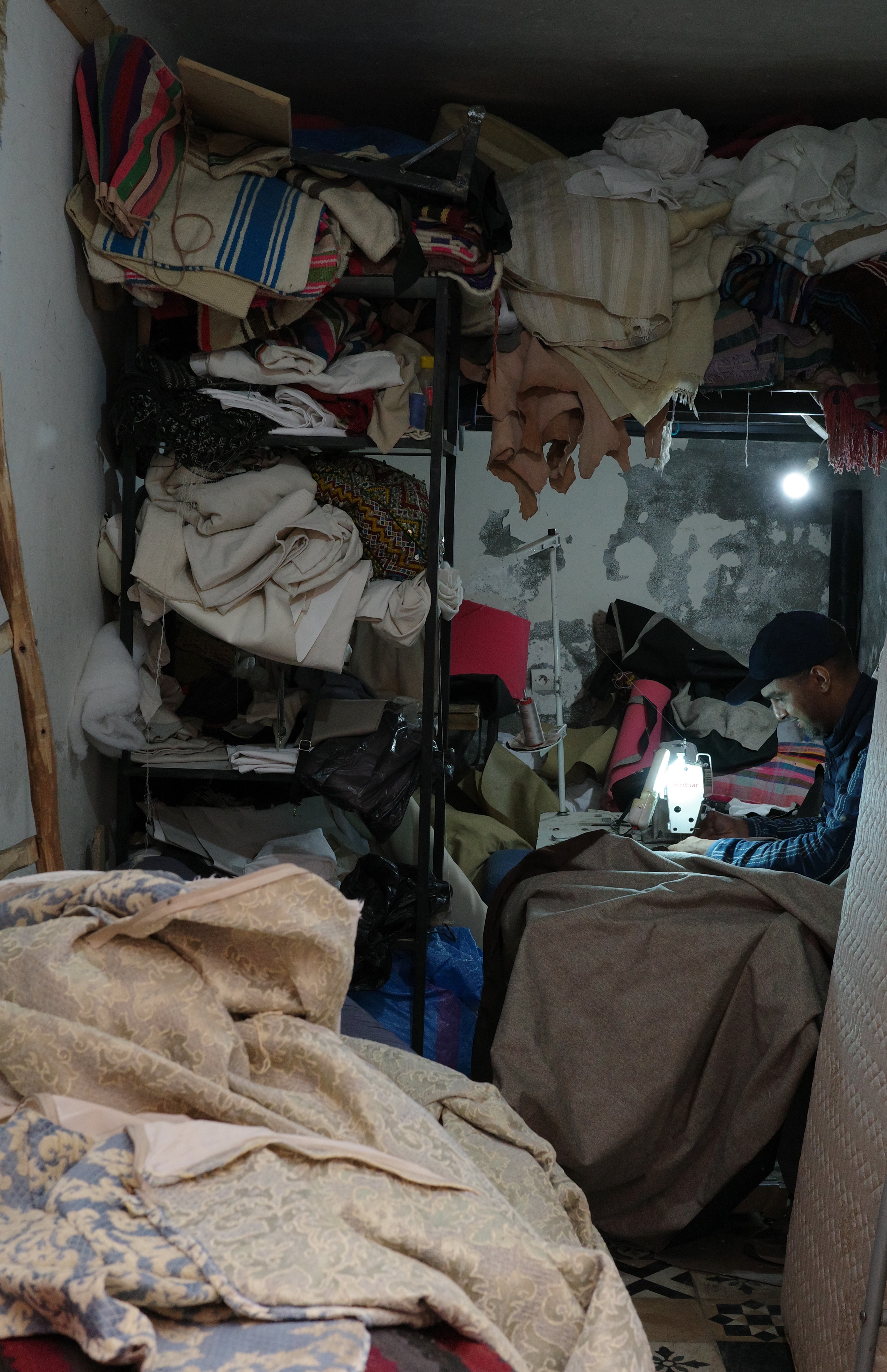 An overhead view into a narrow room filled with folded fabrics and clothing.