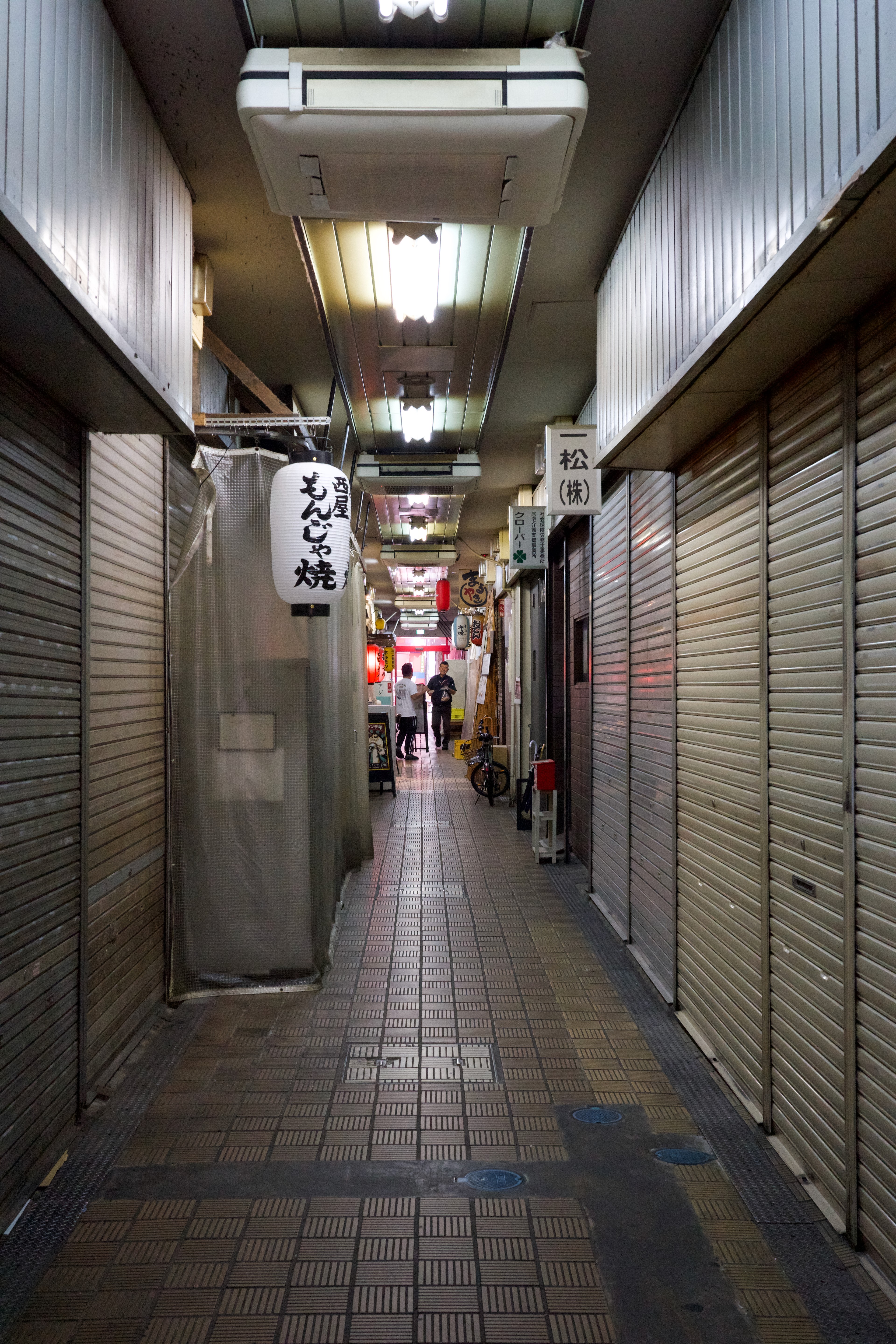 A dim market corridor runs between closed shop shutters.