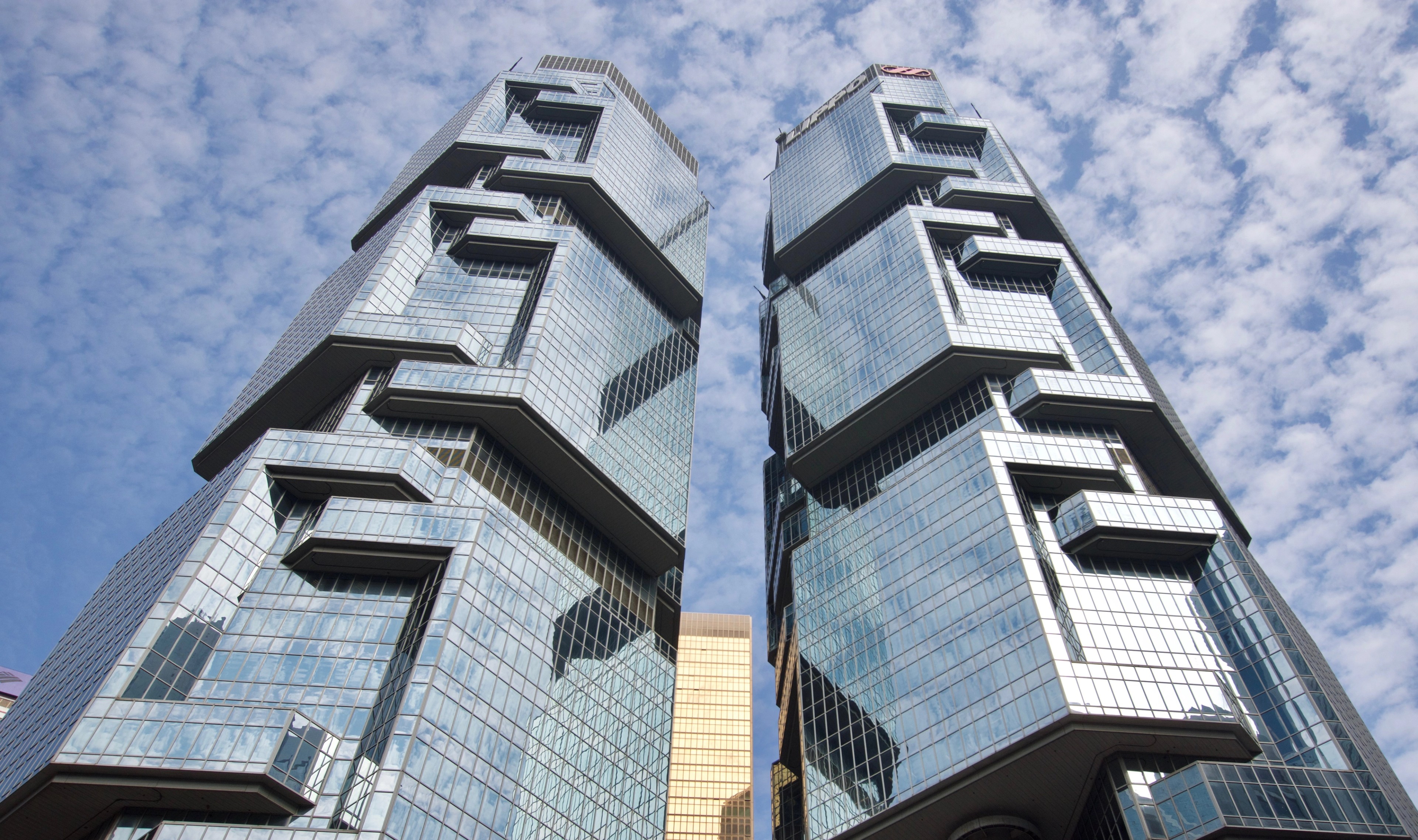 Two modern high-rise buildings are viewed from directly below.