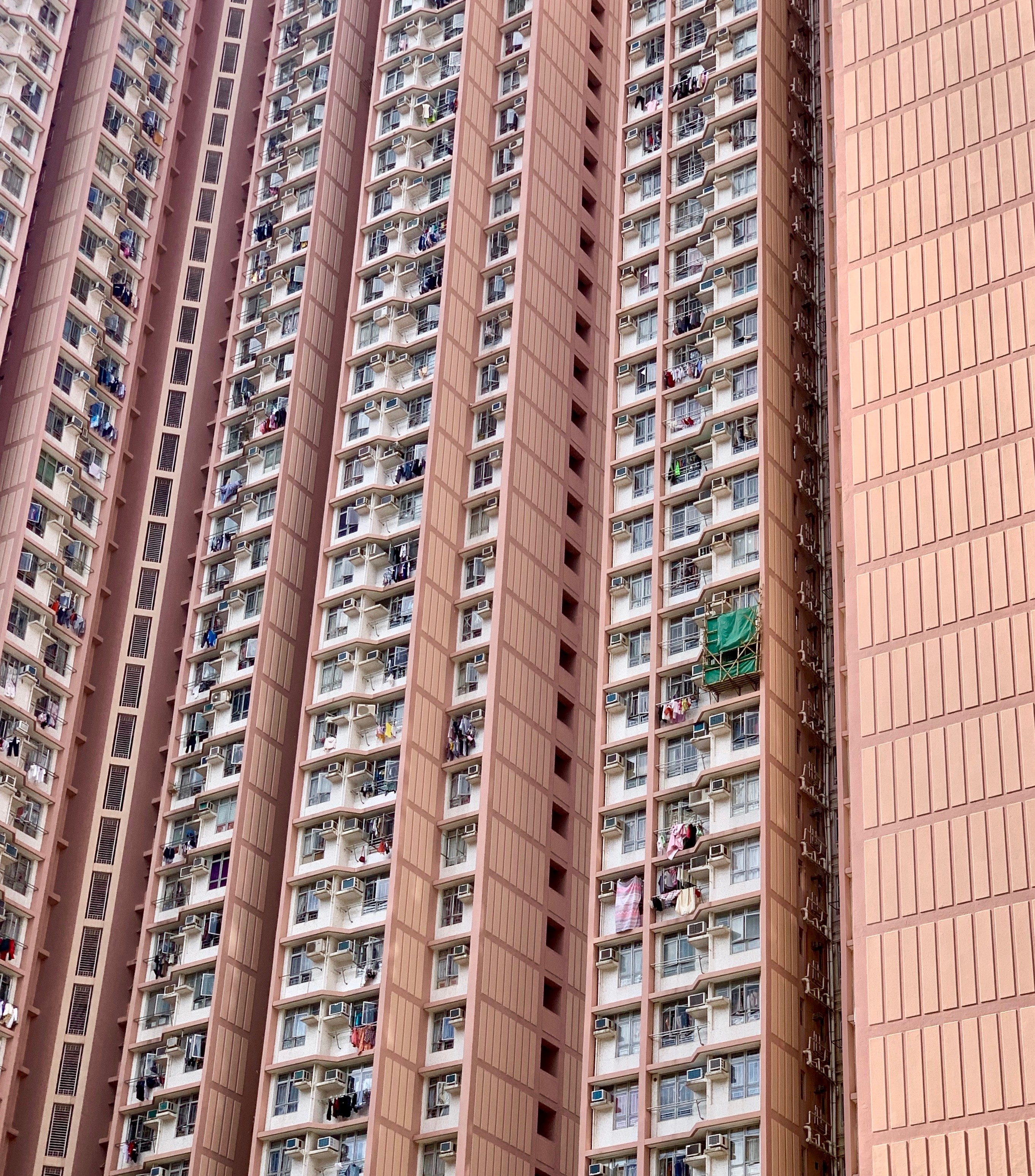 Close view of a pink Hong Kong residential tower with balconies and windows.