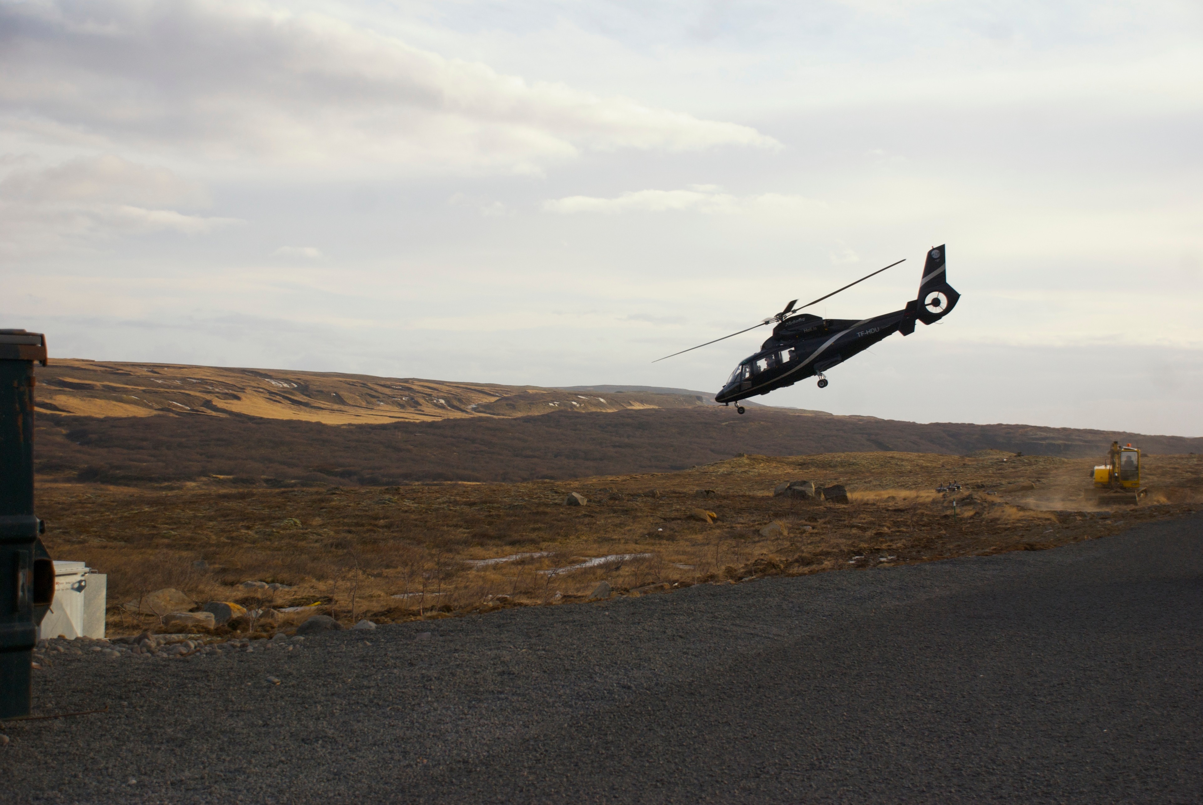 A helicopter flies low over a flat brown landscape.
