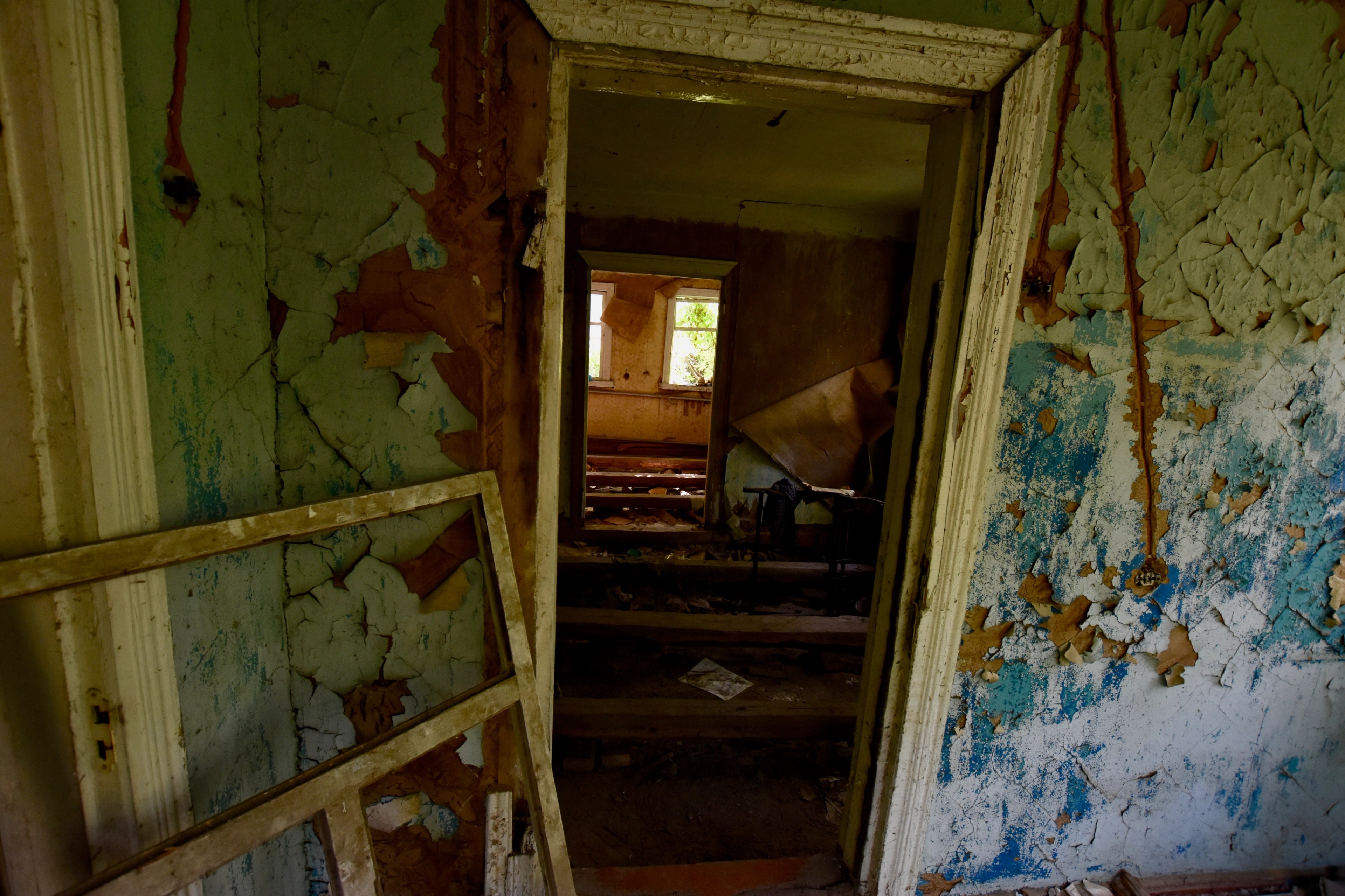 A doorway looks through a hall with peeling paint.