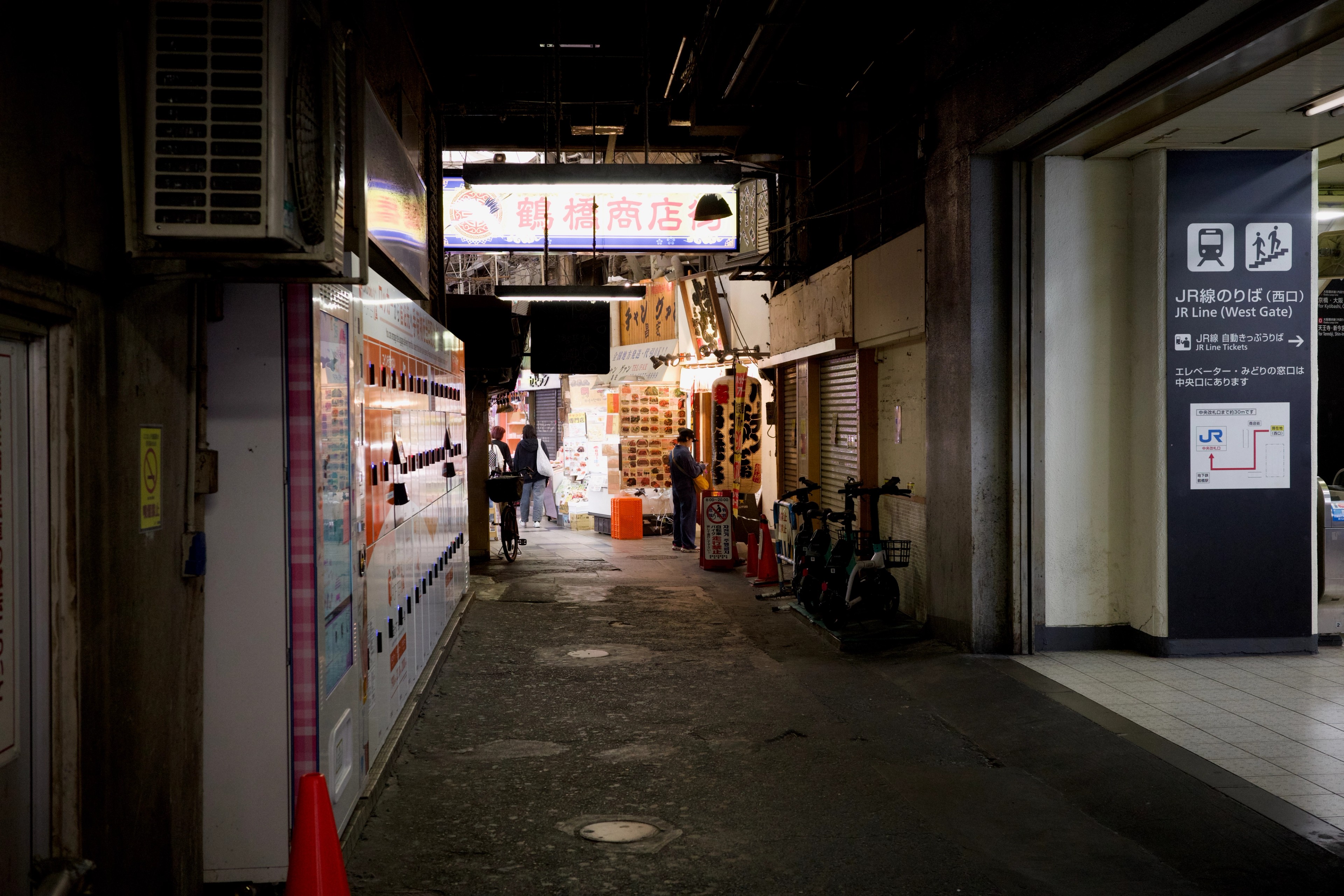 A covered alley with vending machines and closed storefronts.