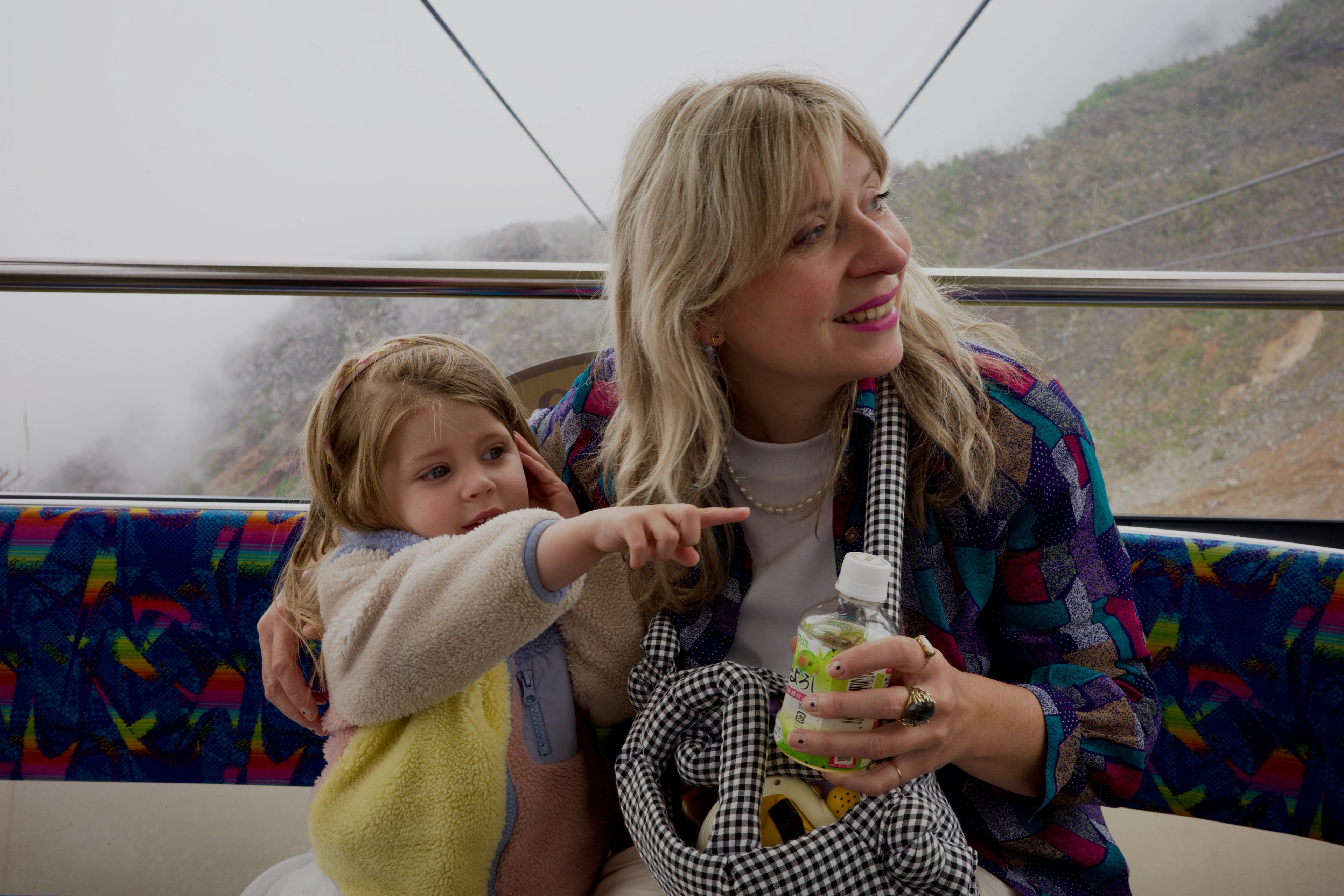 A woman and child point out the cable car window.