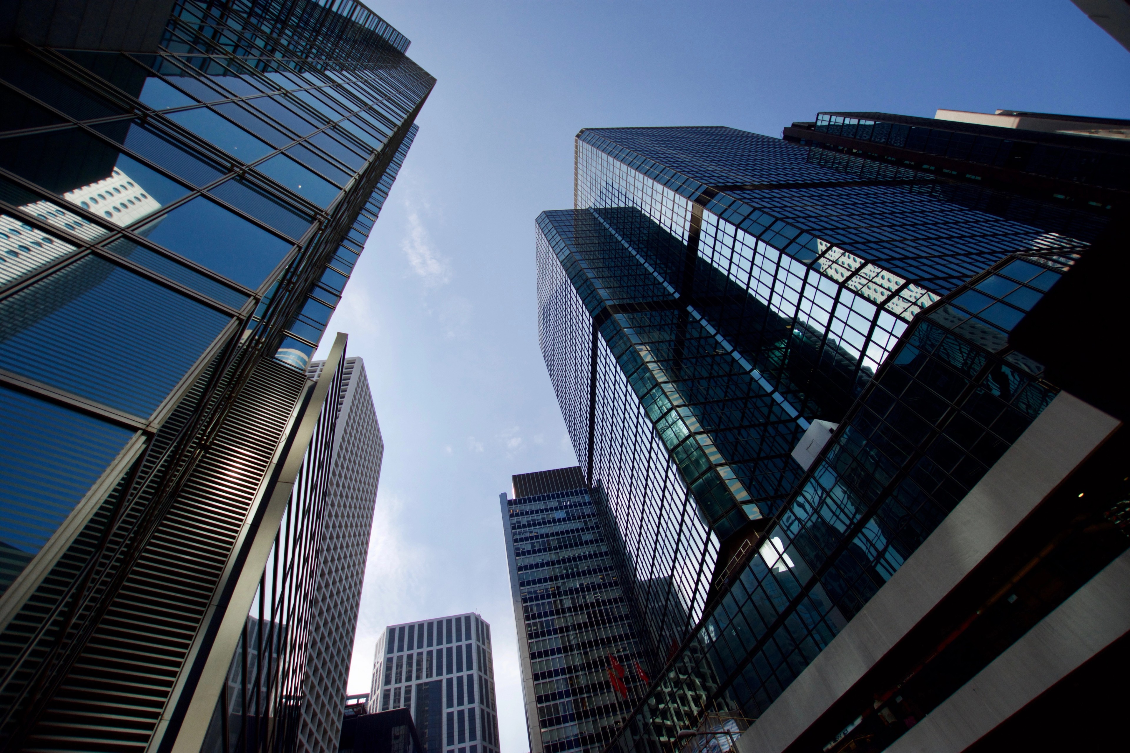 Glass office towers rise overhead against a blue sky.