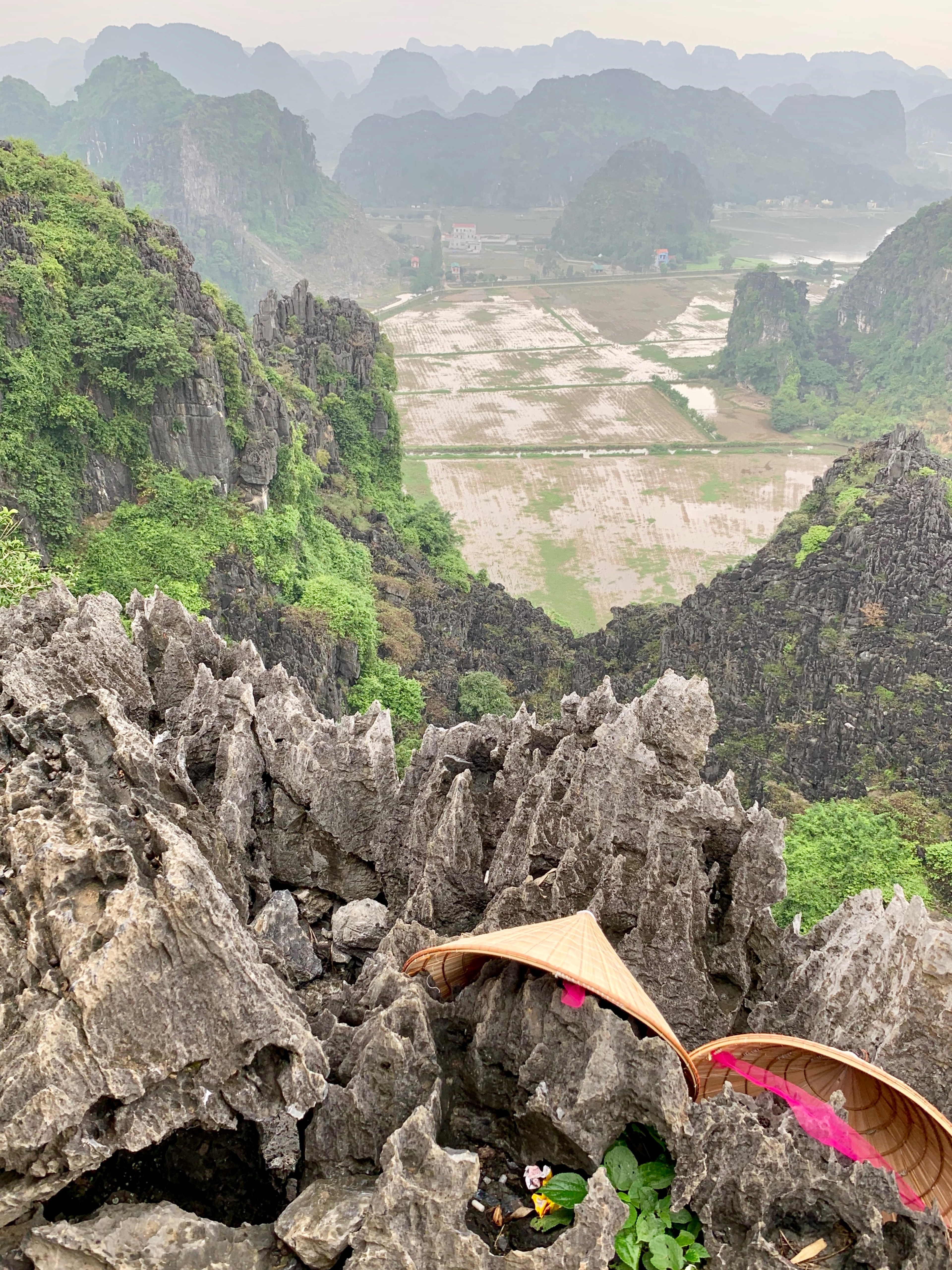 A traveler climbs a rocky mountain path beneath limestone peaks.