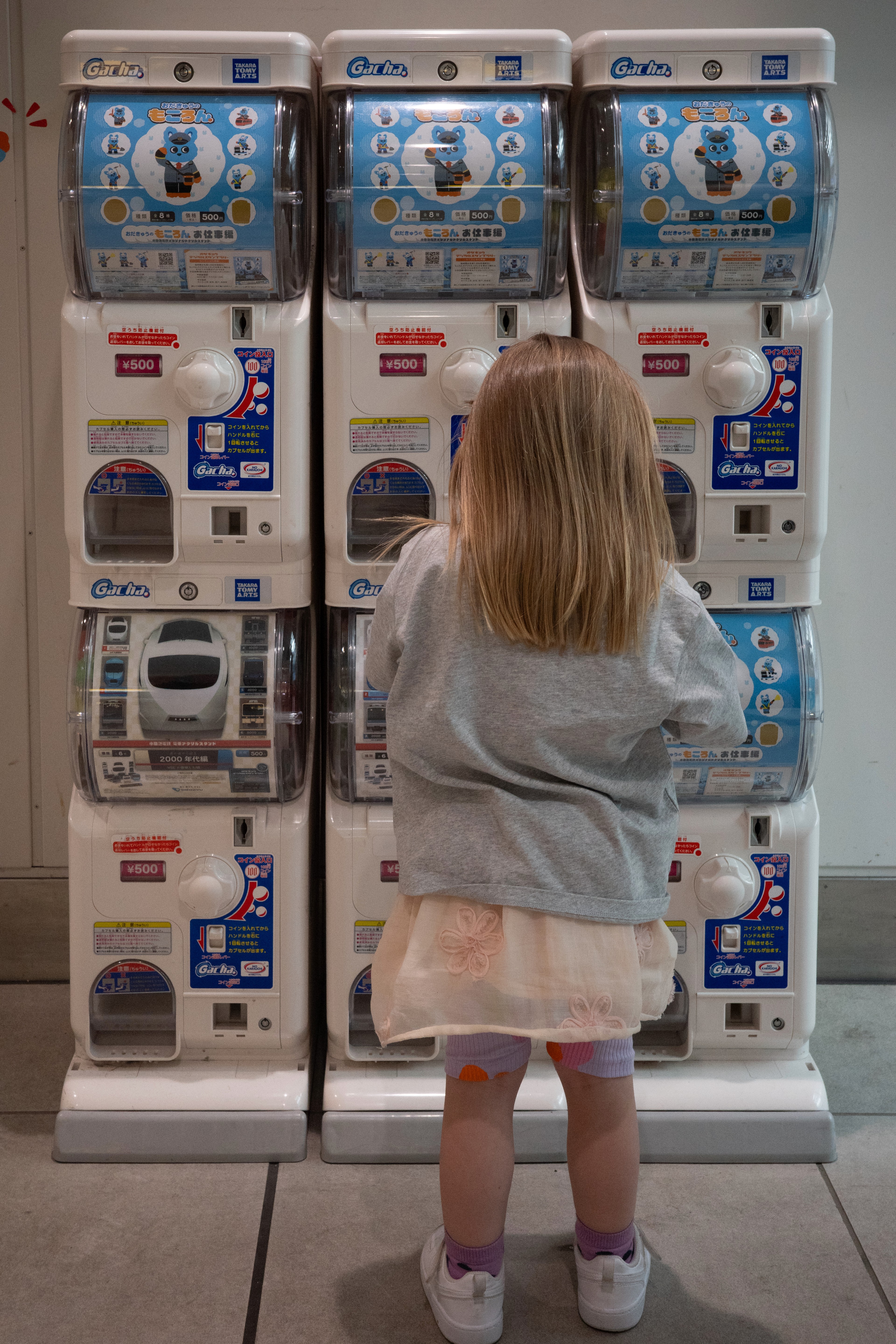 A child stands in front of vending machines.