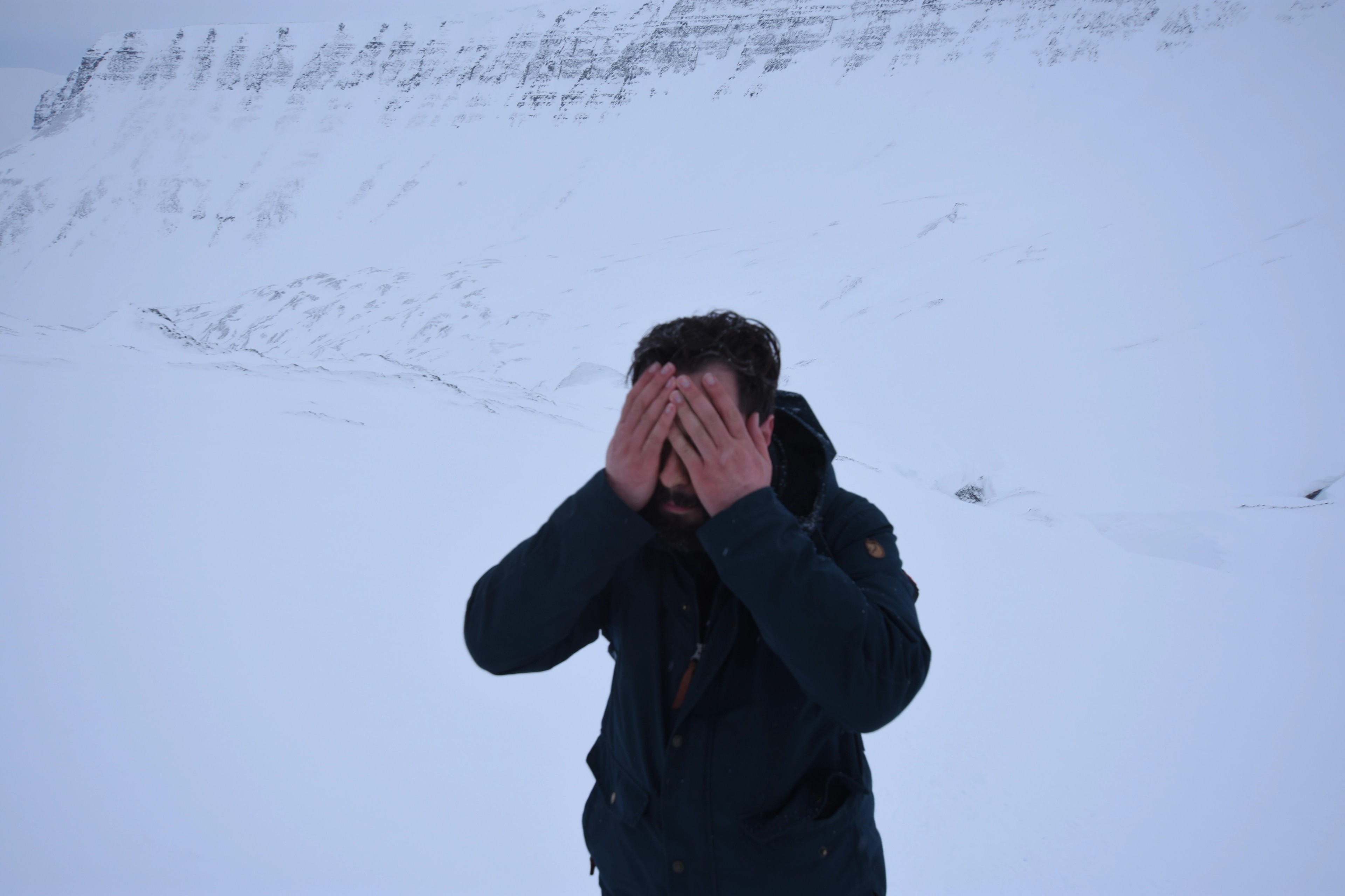 A person shields their face from blowing snow.