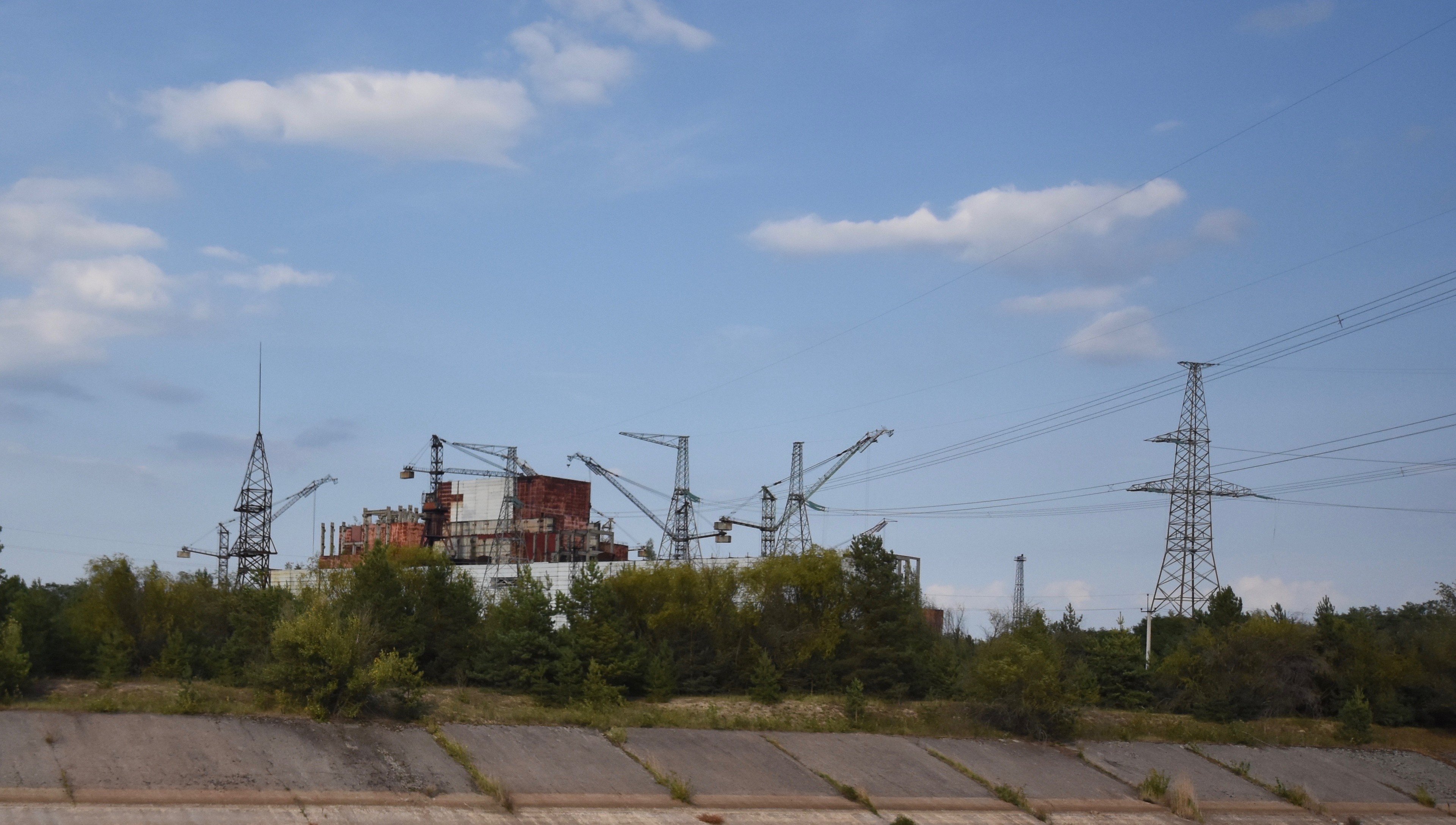 Industrial structures and power pylons beneath a blue sky.