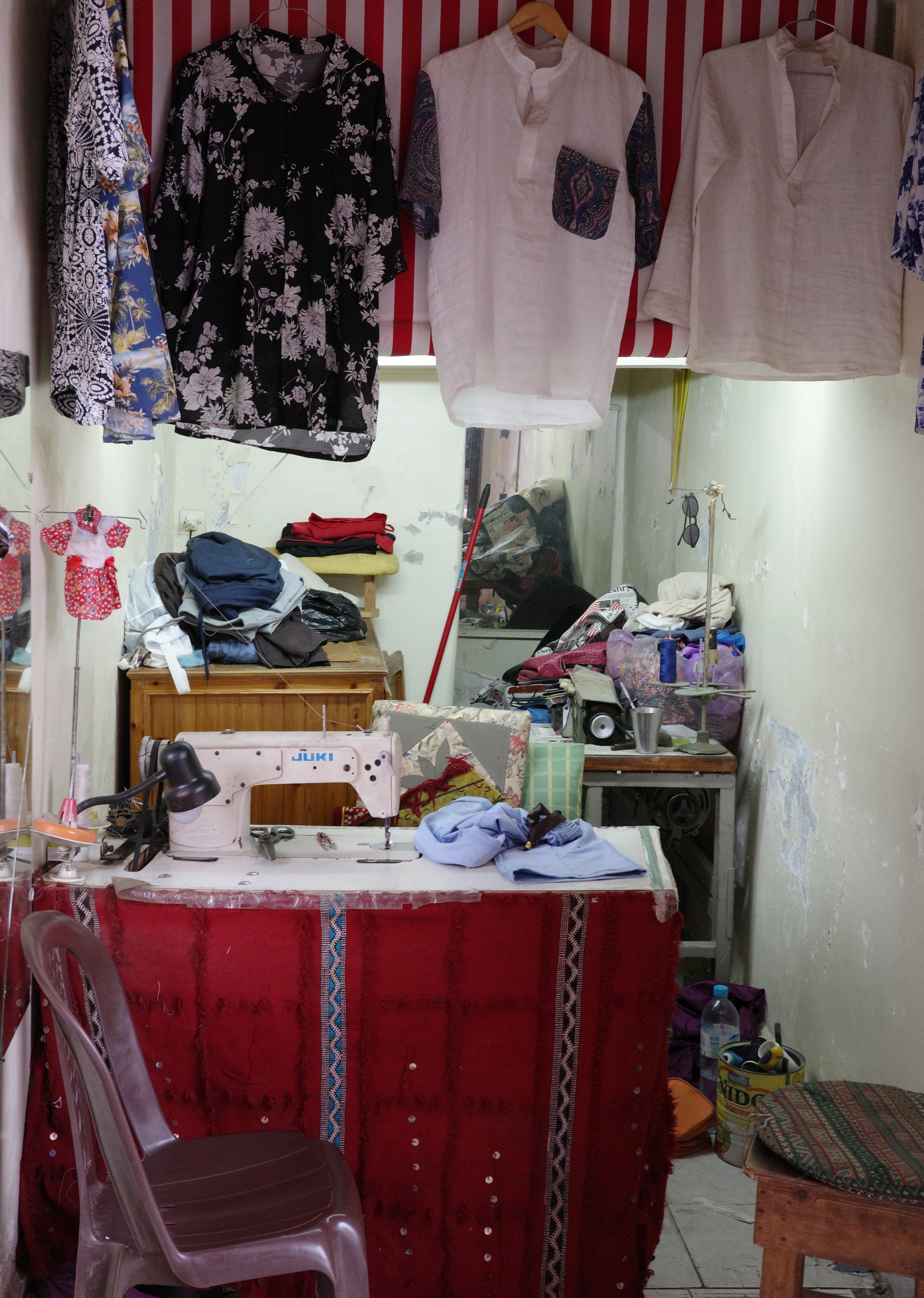 A small clothing shop displays garments and household items at its entrance.