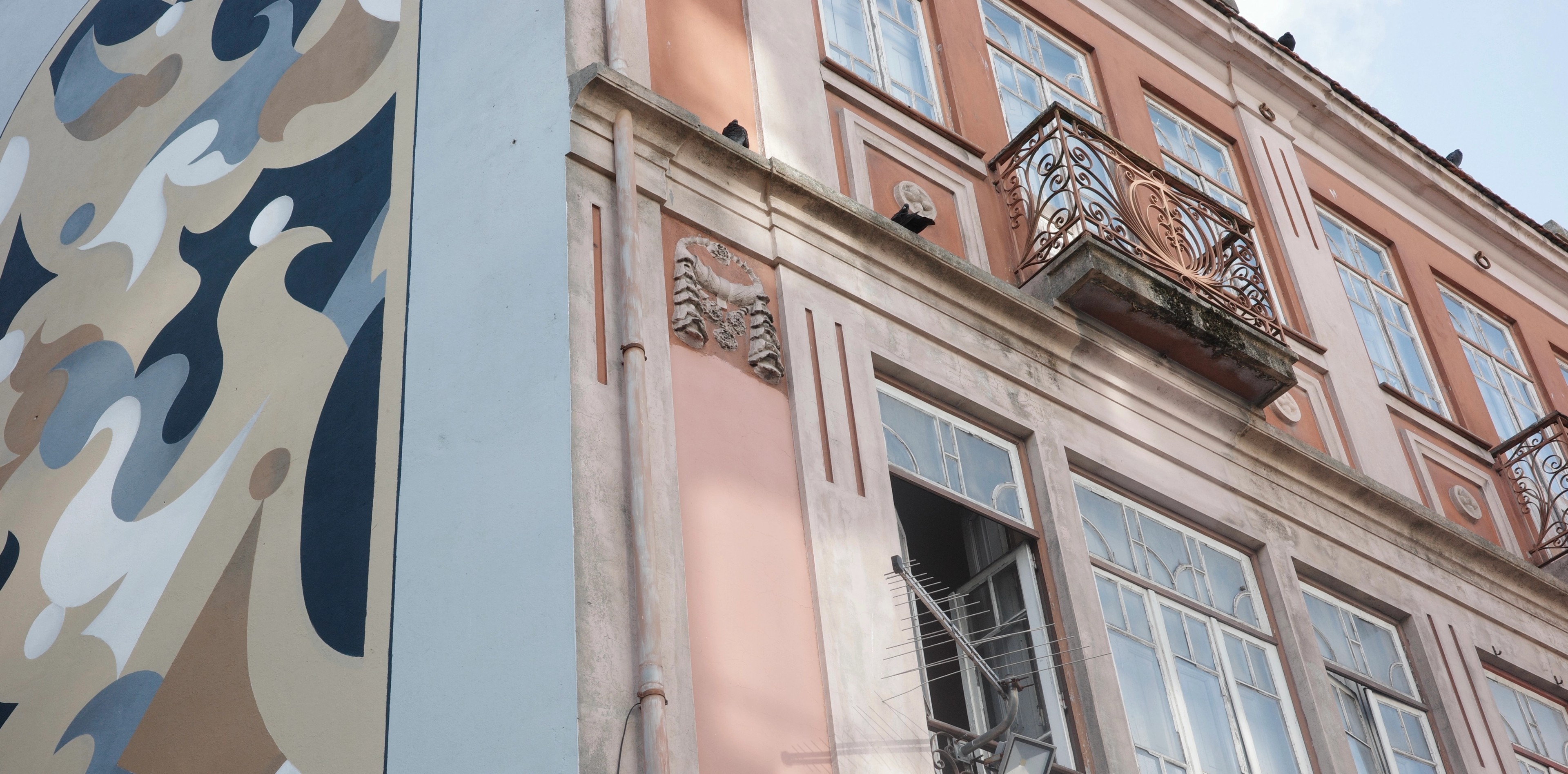 A pink tiled Porto façade rises beside a blue-and-white patterned wall.