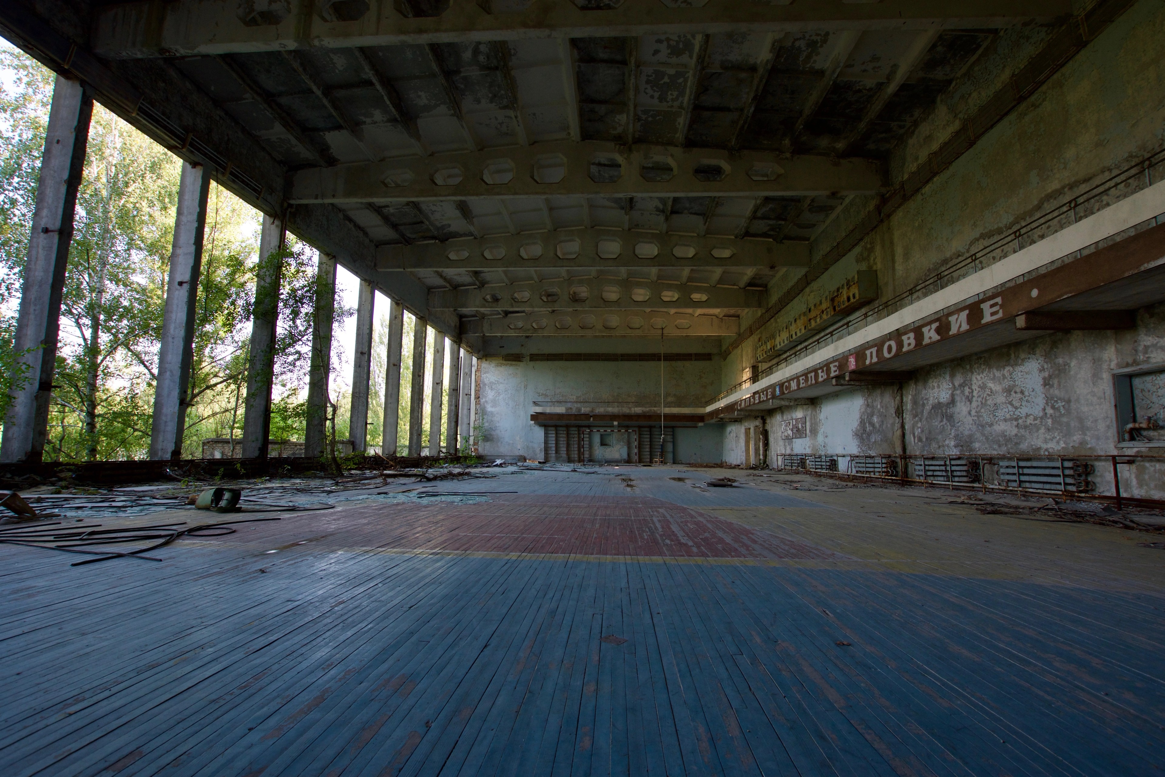 A broad hall with a blue floor and tall windows.
