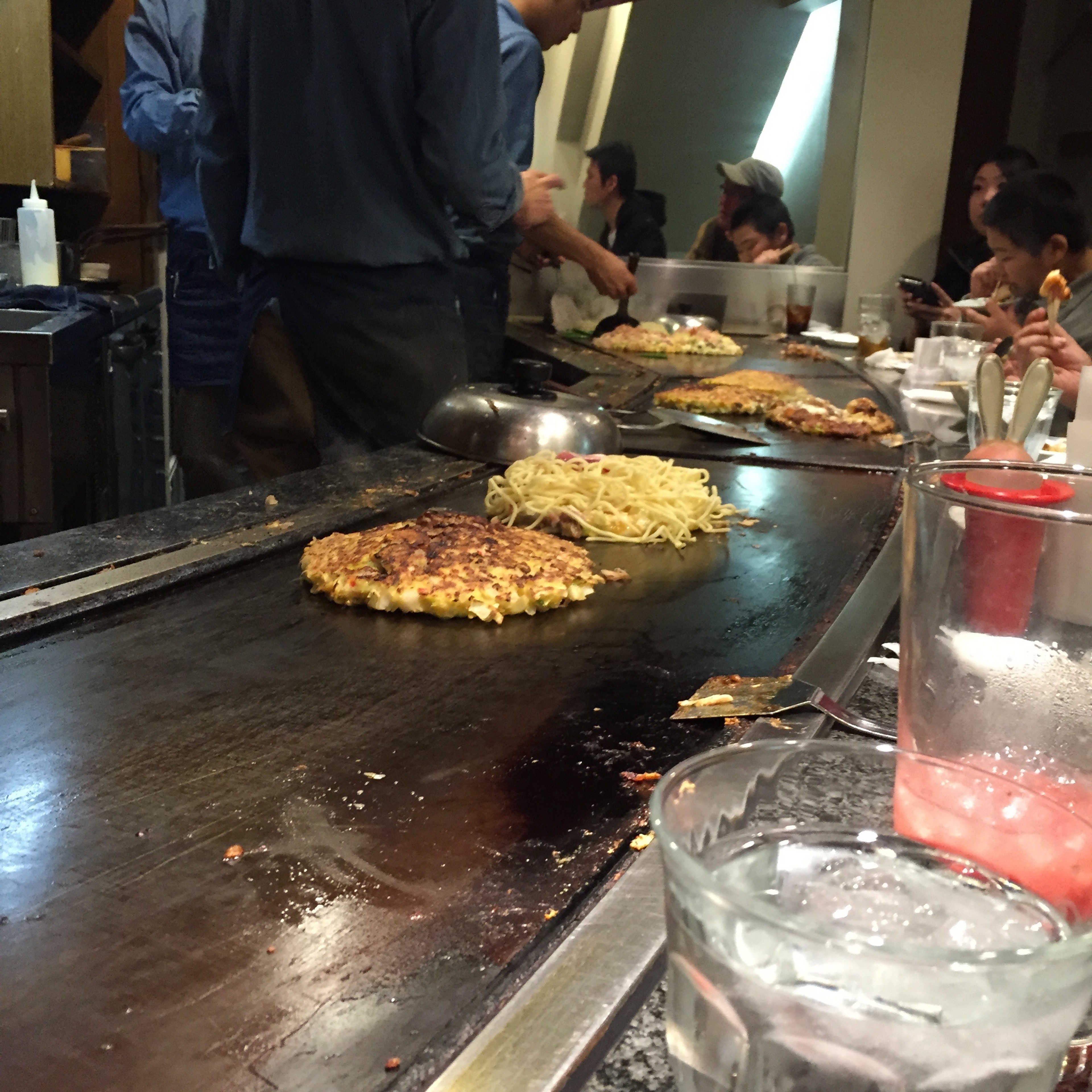 A cook prepares food on a large flat iron griddle.