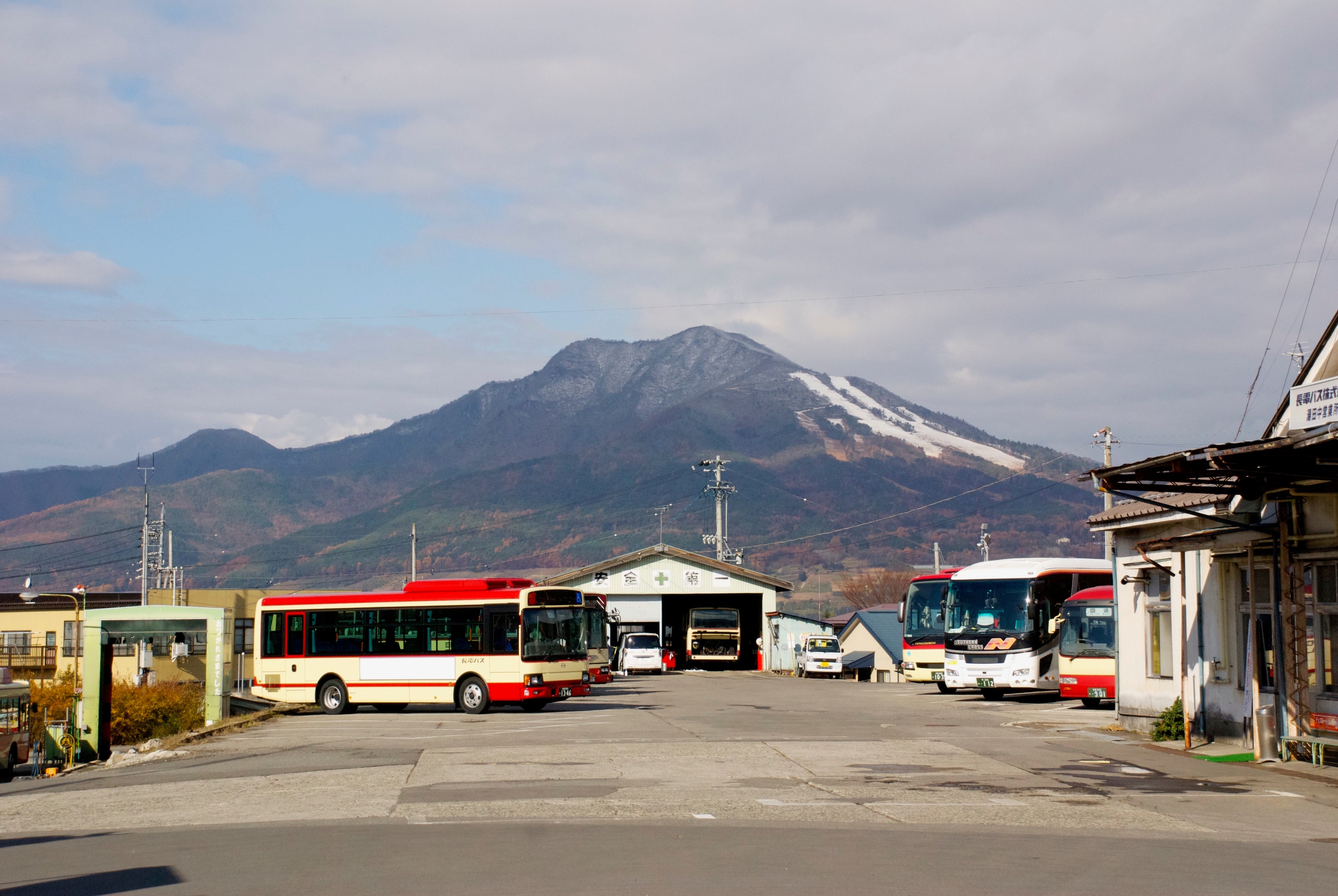 A bus station and low buildings sit beneath a mountain.