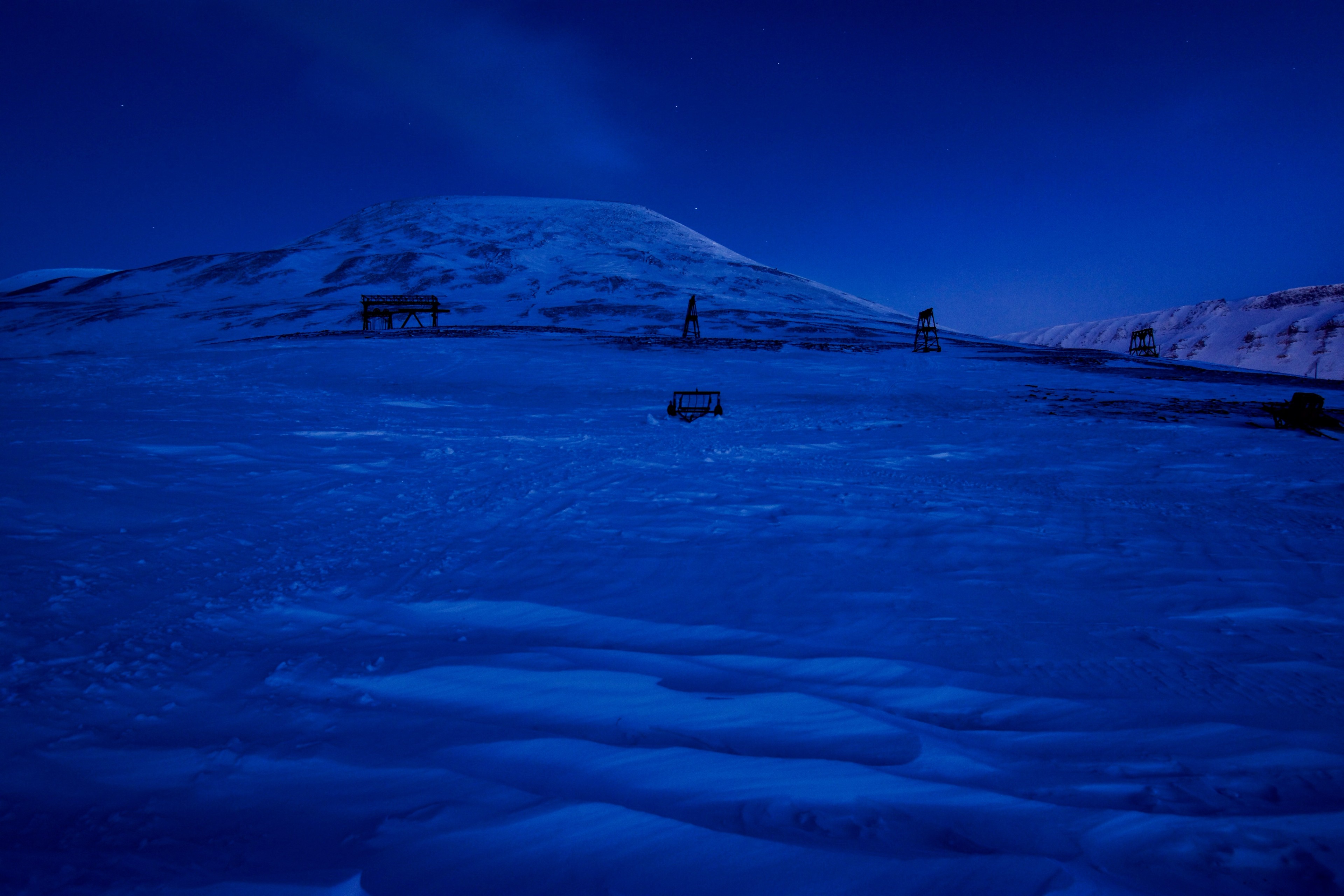 A vehicle crosses a frozen landscape at dusk.